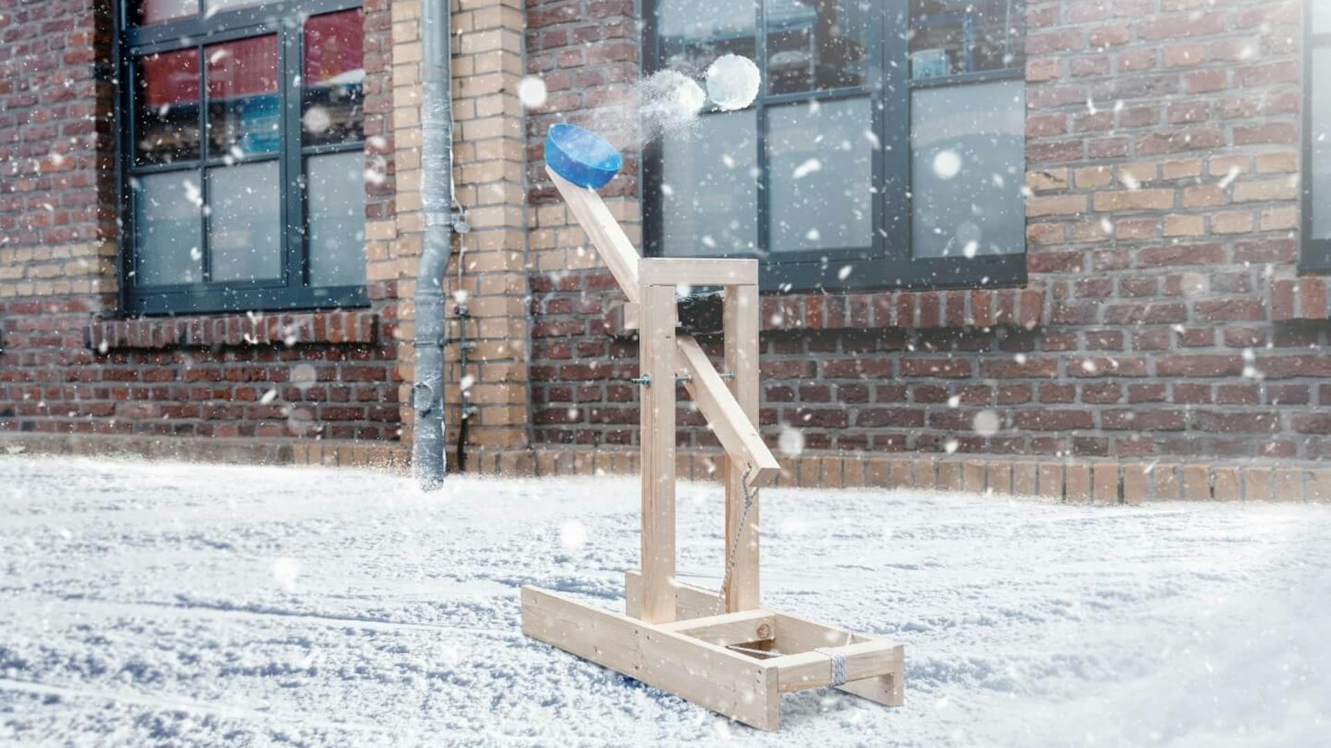 Schneeball-Katapult steht vor einem Haus im Schnee