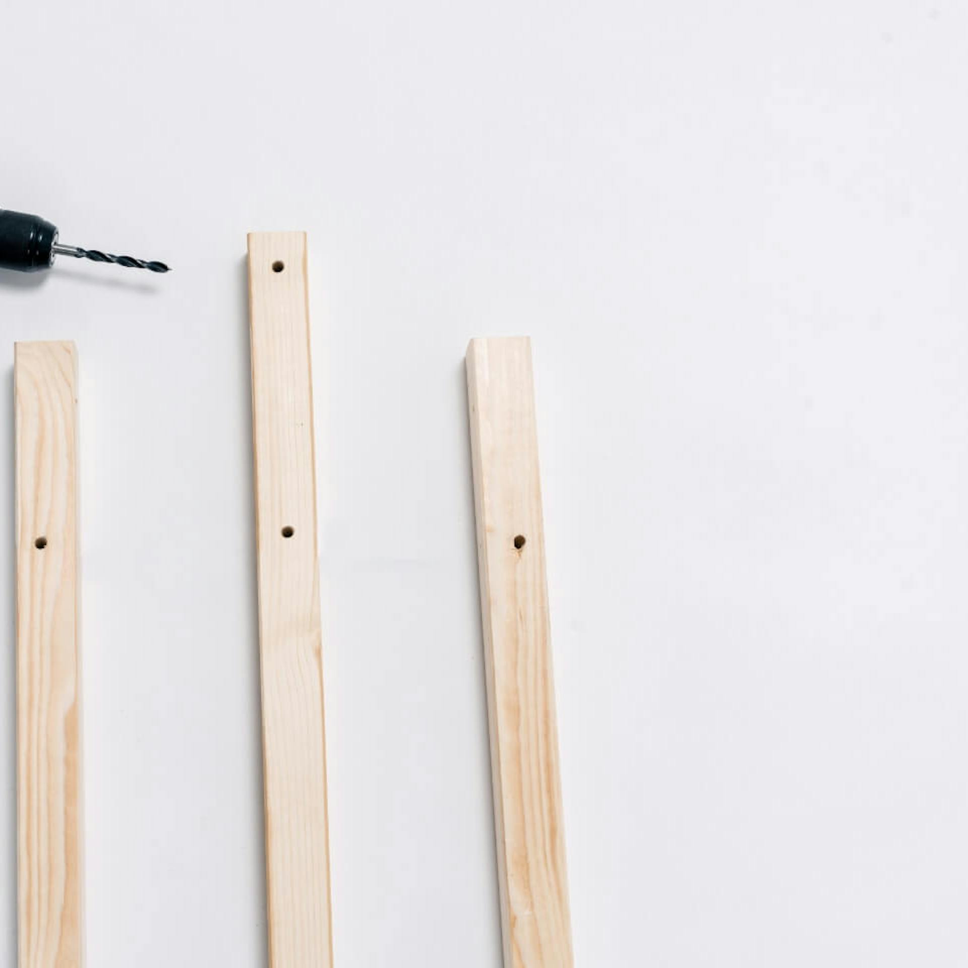 ein langes Kantholz mit zwei Löchern, zwei kürzere Kanthölzer mit einem Loch