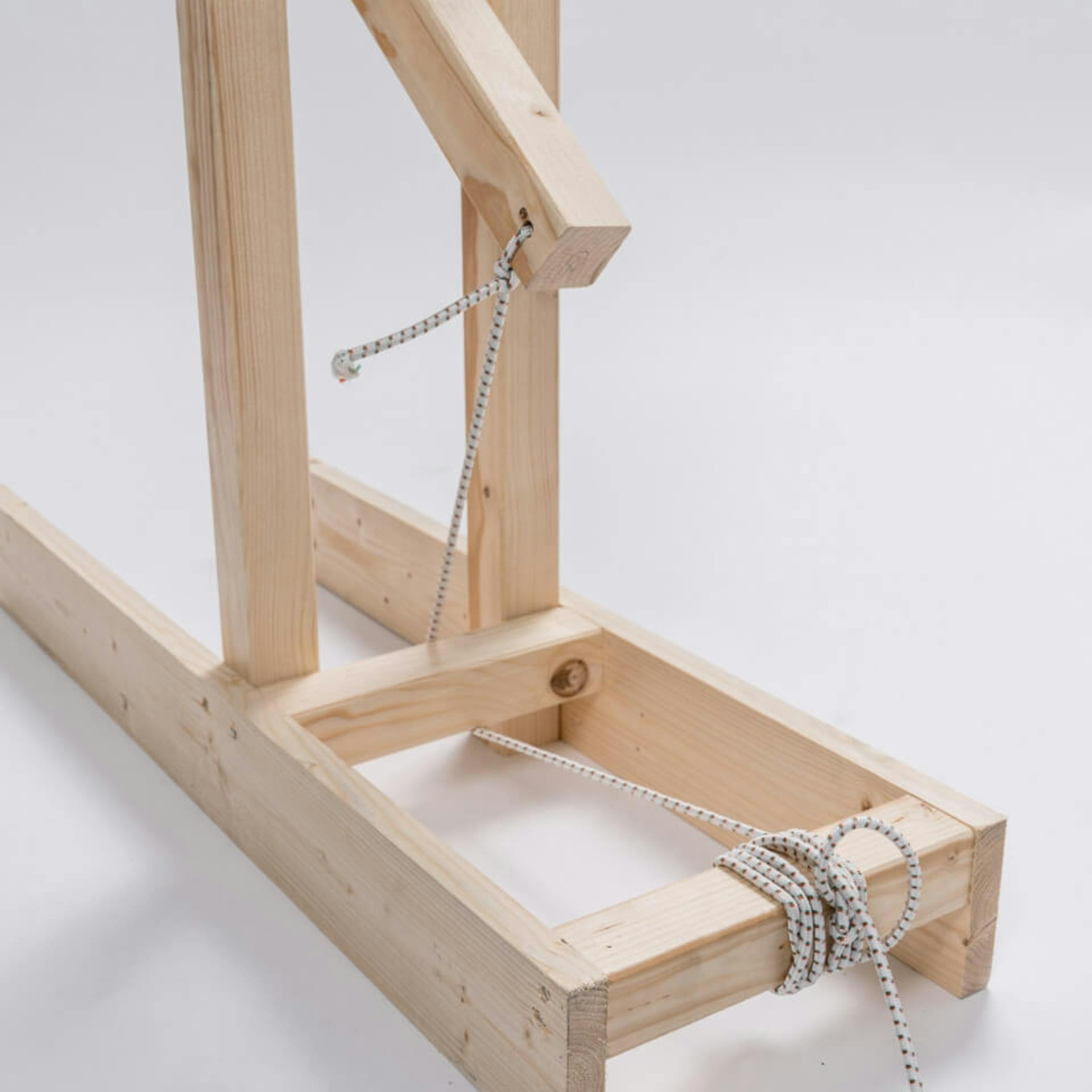 Seil am Fußteil und am beweglichen Teil des Katapults verknotet.