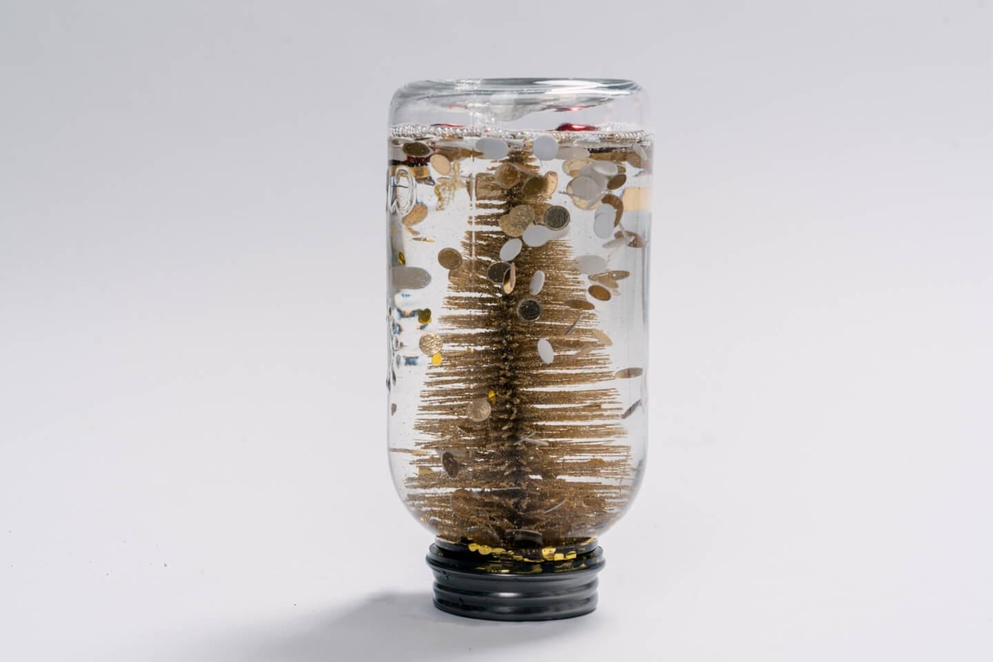 Palla di vetro con la neve fai da te con piccolo albero di Natale artificiale e brillantini