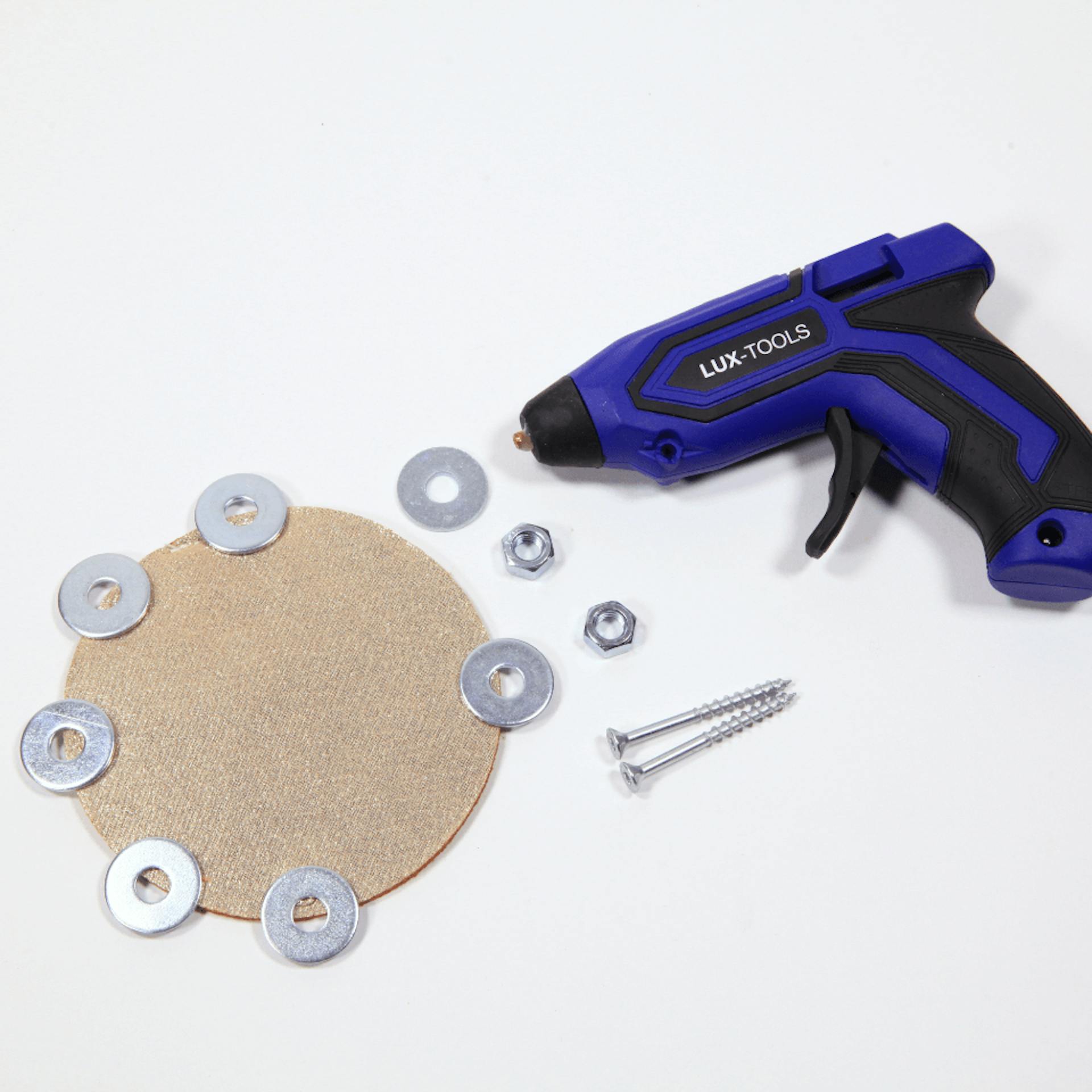 Ein rundes Stück Pappe, darauf liegen einige Unterlegscheiben, daneben Muttern und eine Schraube sowie eine Heißklebepistole.