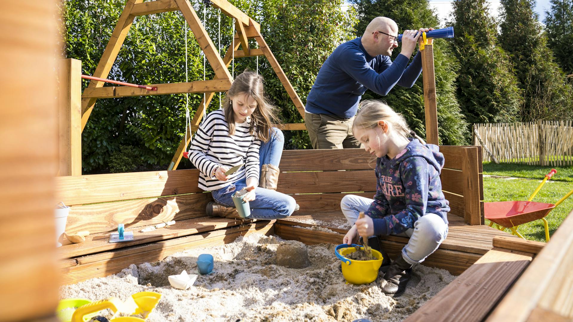 Kinder spielen im Sandkasten mit Utensilien