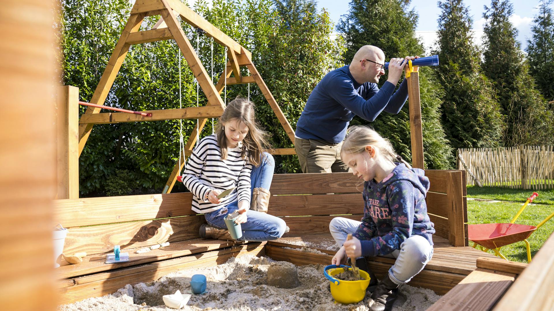 Vater und zwei Töchter in Sandkasten