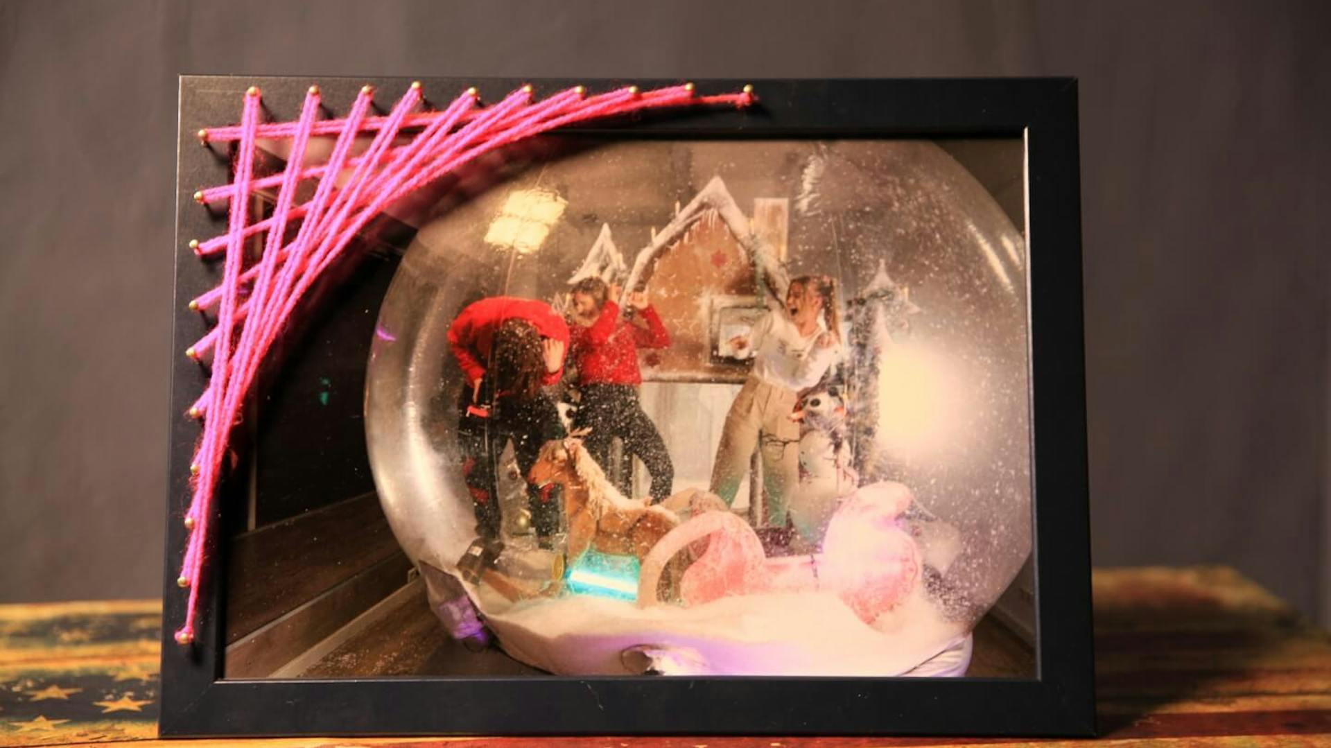 Der fertige Bilderrahmen mit String Art steht auf einer hölzernen Oberfläche.