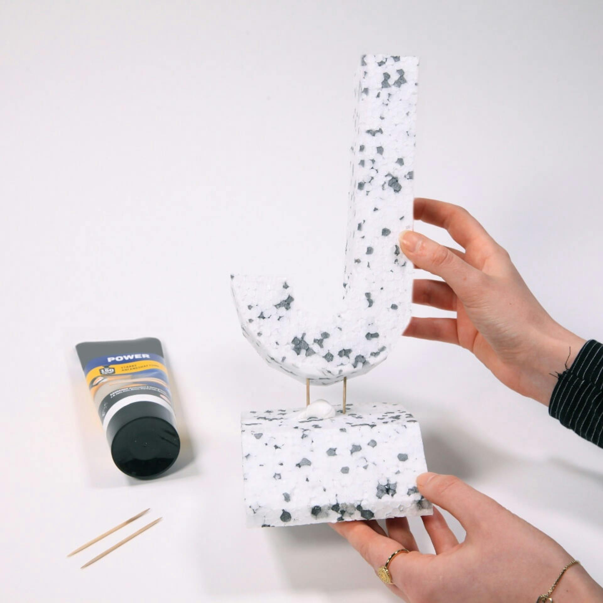 Eine Person befestigt die Form aus Styropor auf einem Ständer.