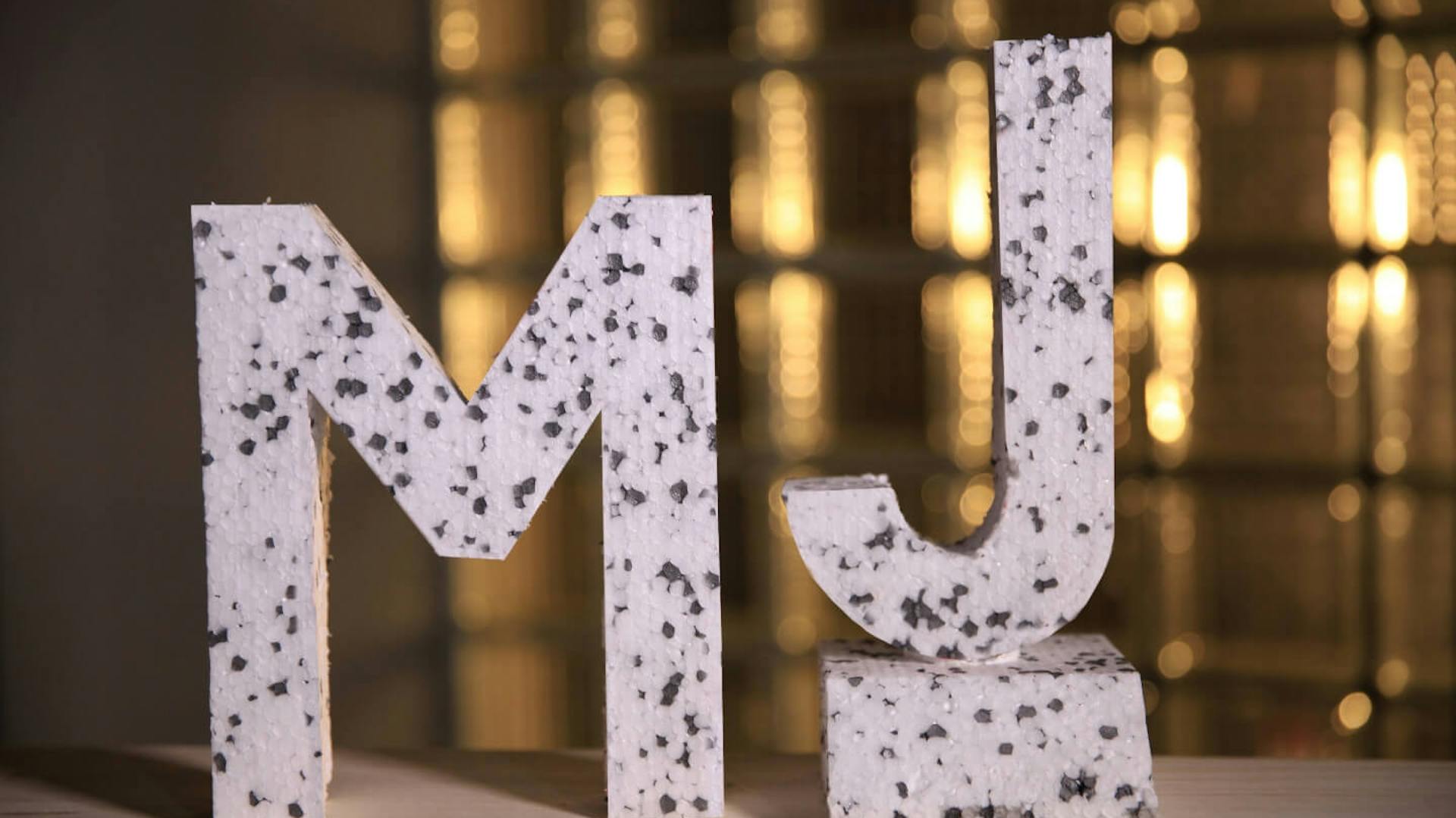 Die Buchstaben M und J als Styropor-Figuren stehen auf einem Tisch.