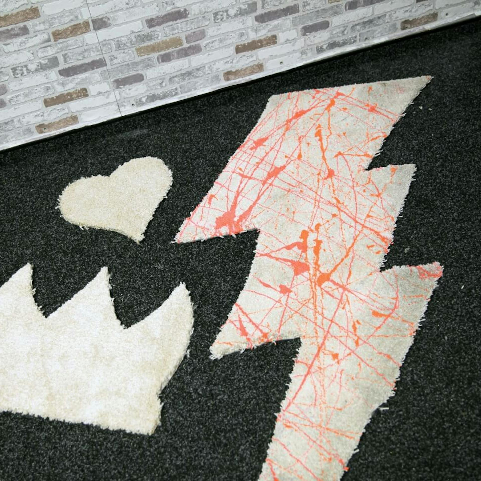 Tappeto a forma di lampo con schizzi di vernice arancione.