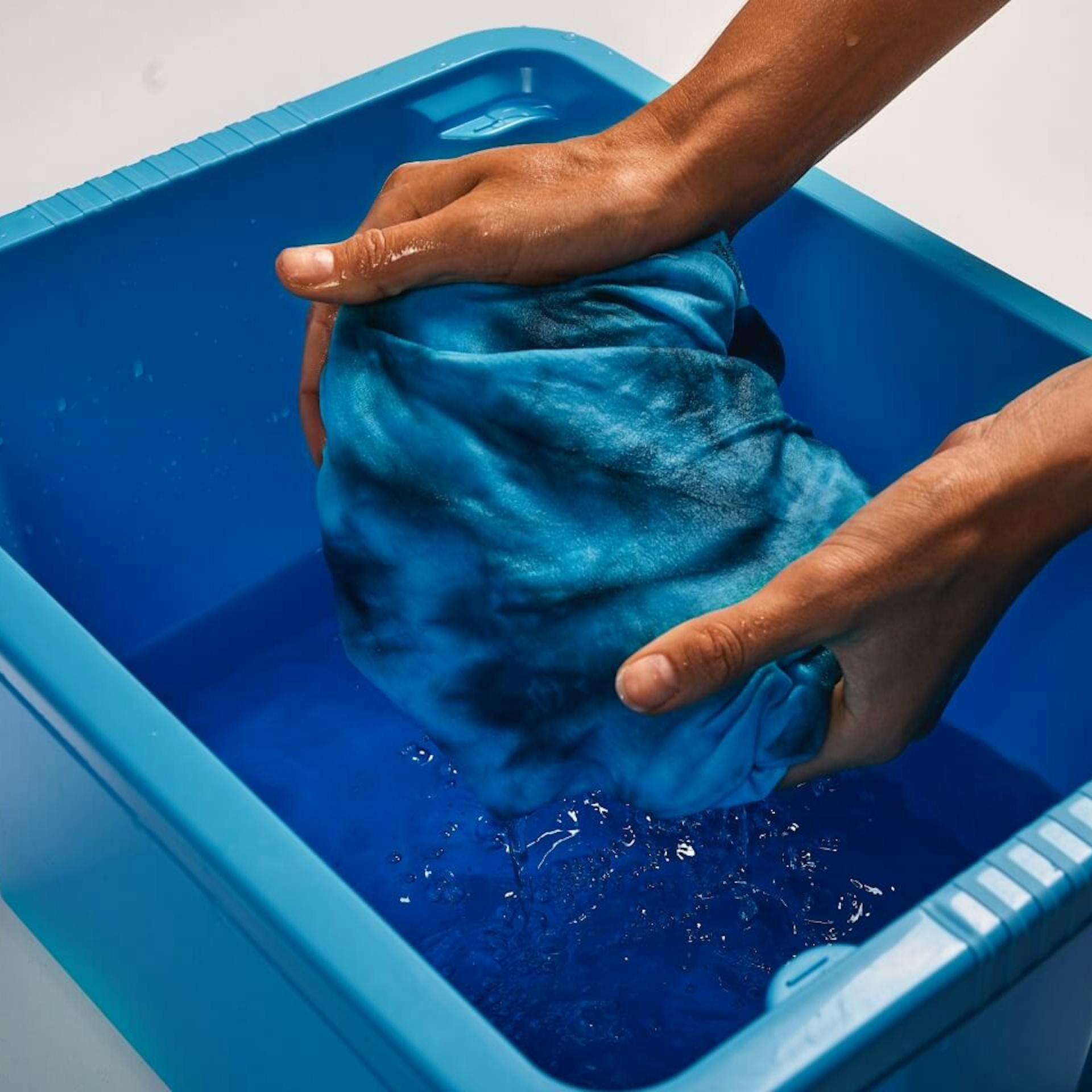 Ein Person wringt ein gefärbtes T-Shirt aus.