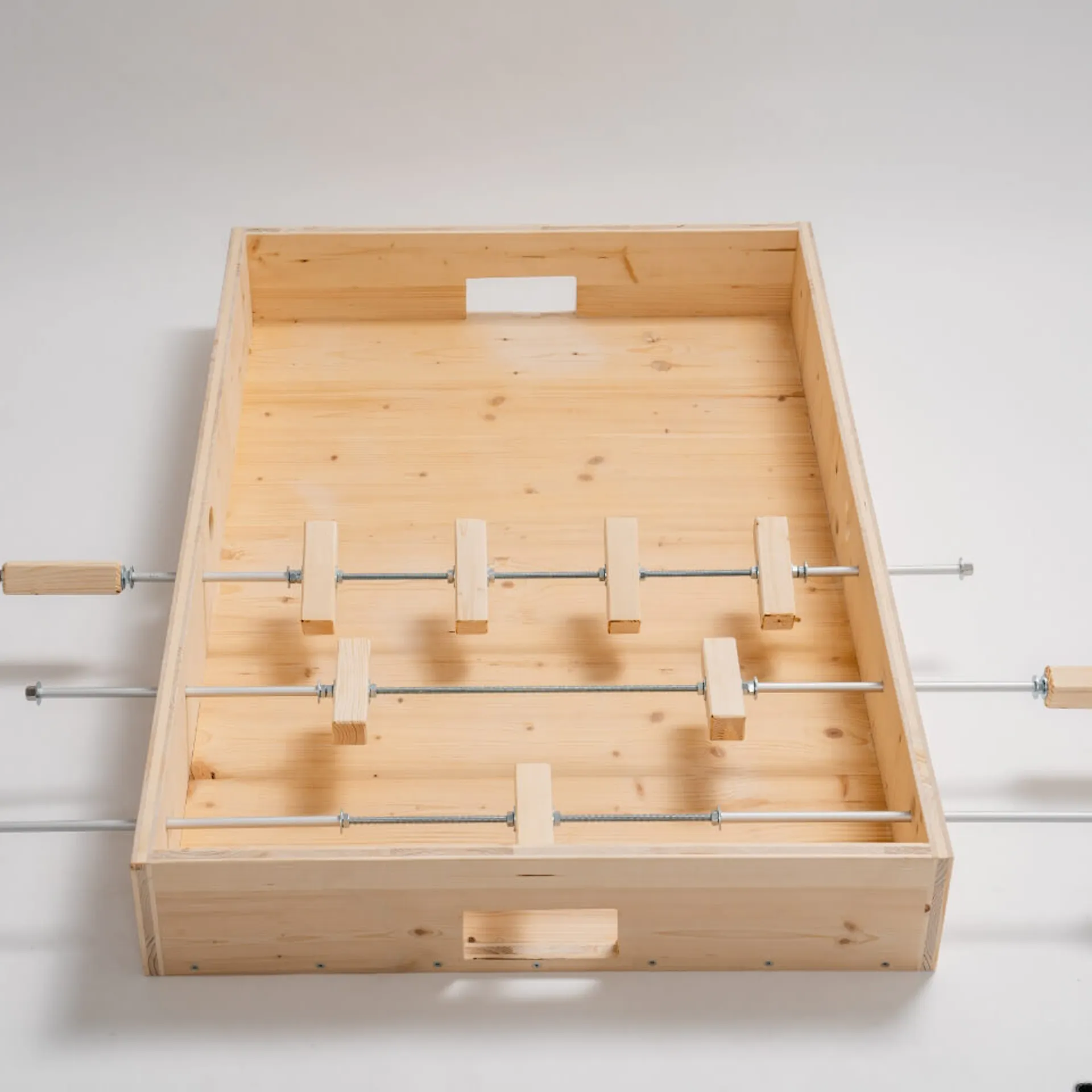 Fotbalový stůl ve výstavbě, tři stolní tyče s několika figurkami.