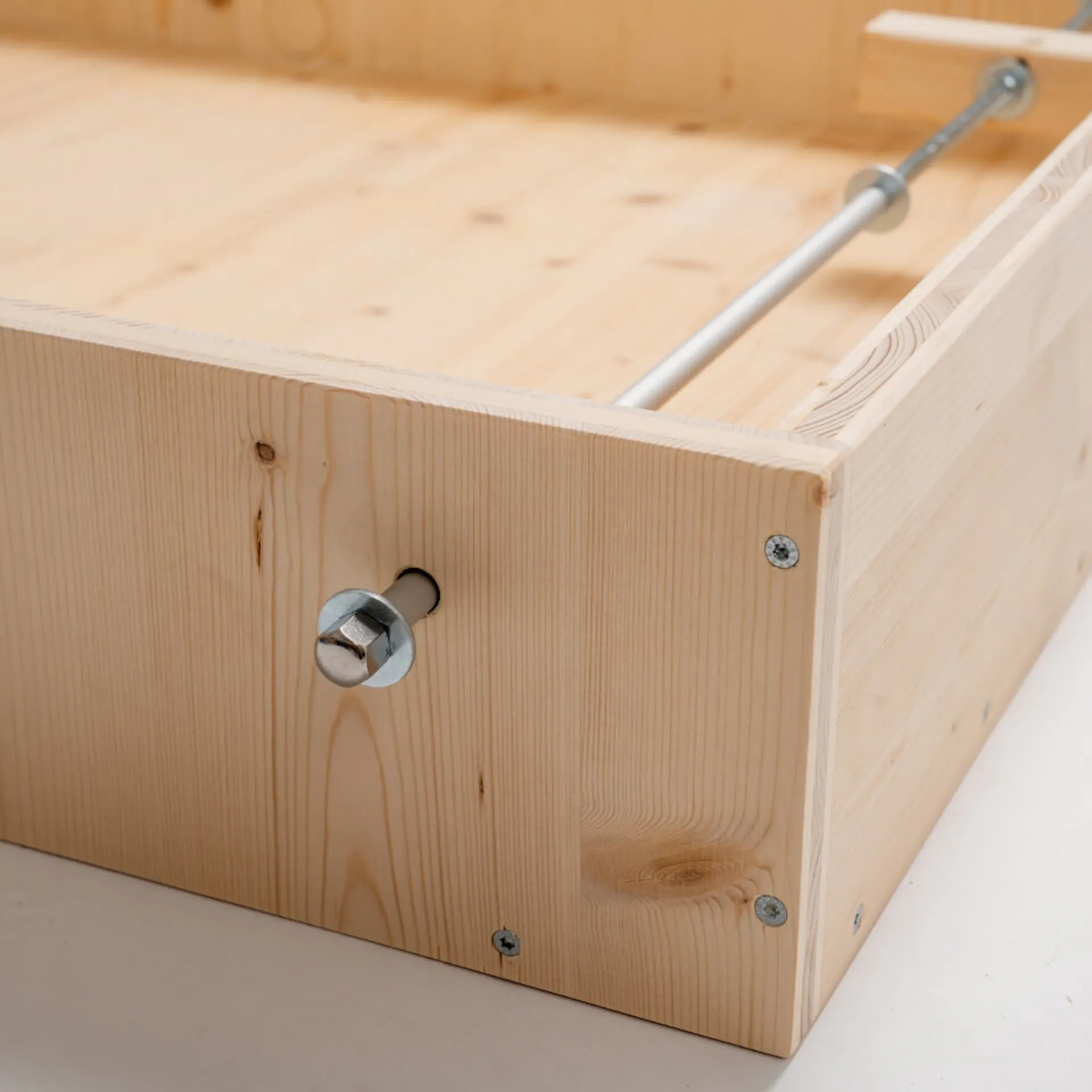 Závitová tyč v dřevěné konstrukci, upevněná podložkou a maticí.