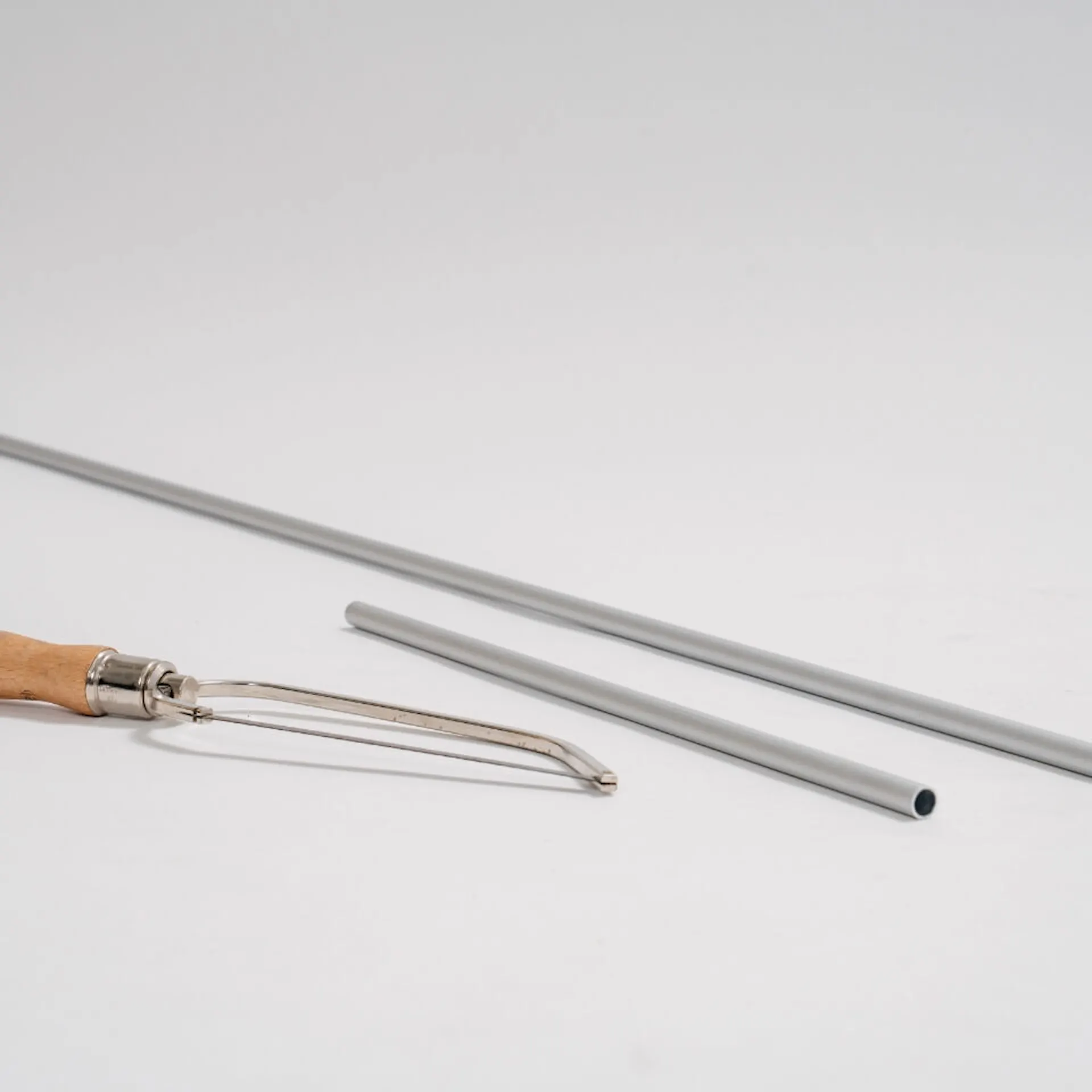 Dvě hliníkové trubky různých délek, před nimi je pila na železo.