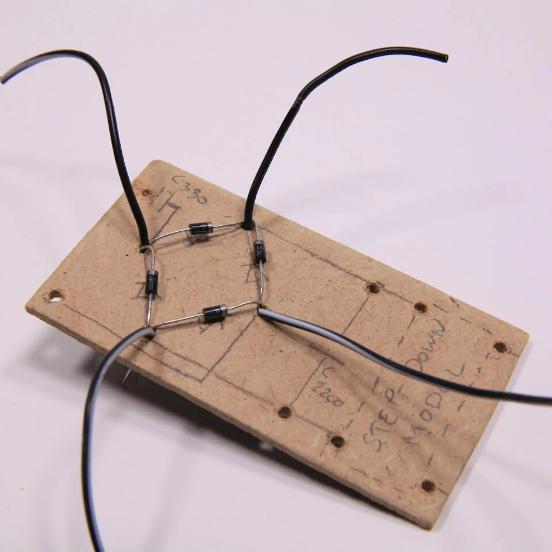 Vier Kabel durchgesteckt durch ein Holzbrett mit Schaltplan und befestigten Dioden