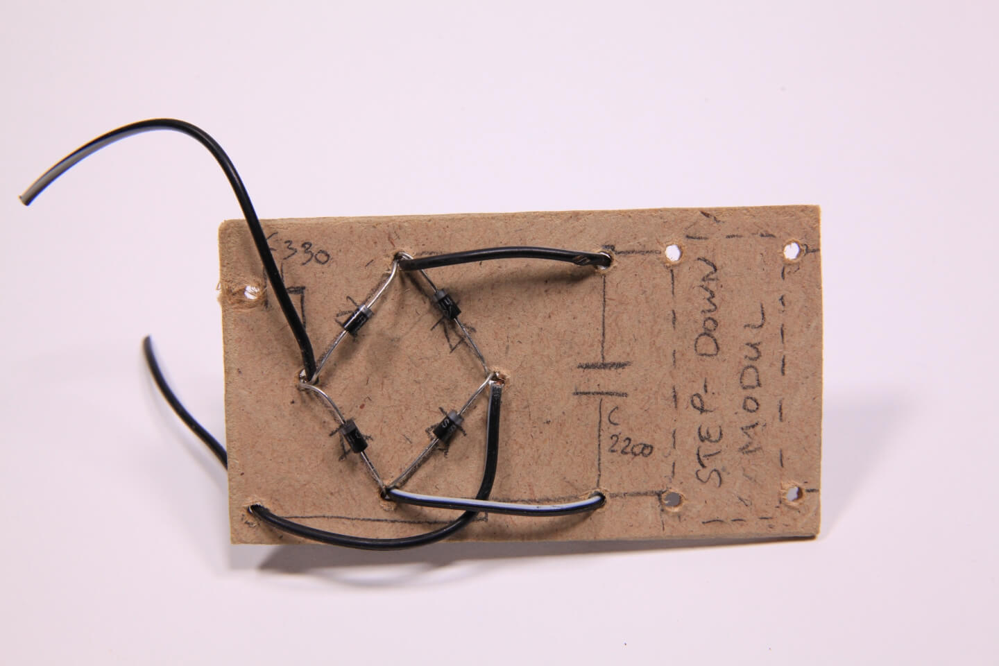 Kabel durch Bohrlöcher gesteckt durch eine Holzplatte mit Schaltplan und Dioden.