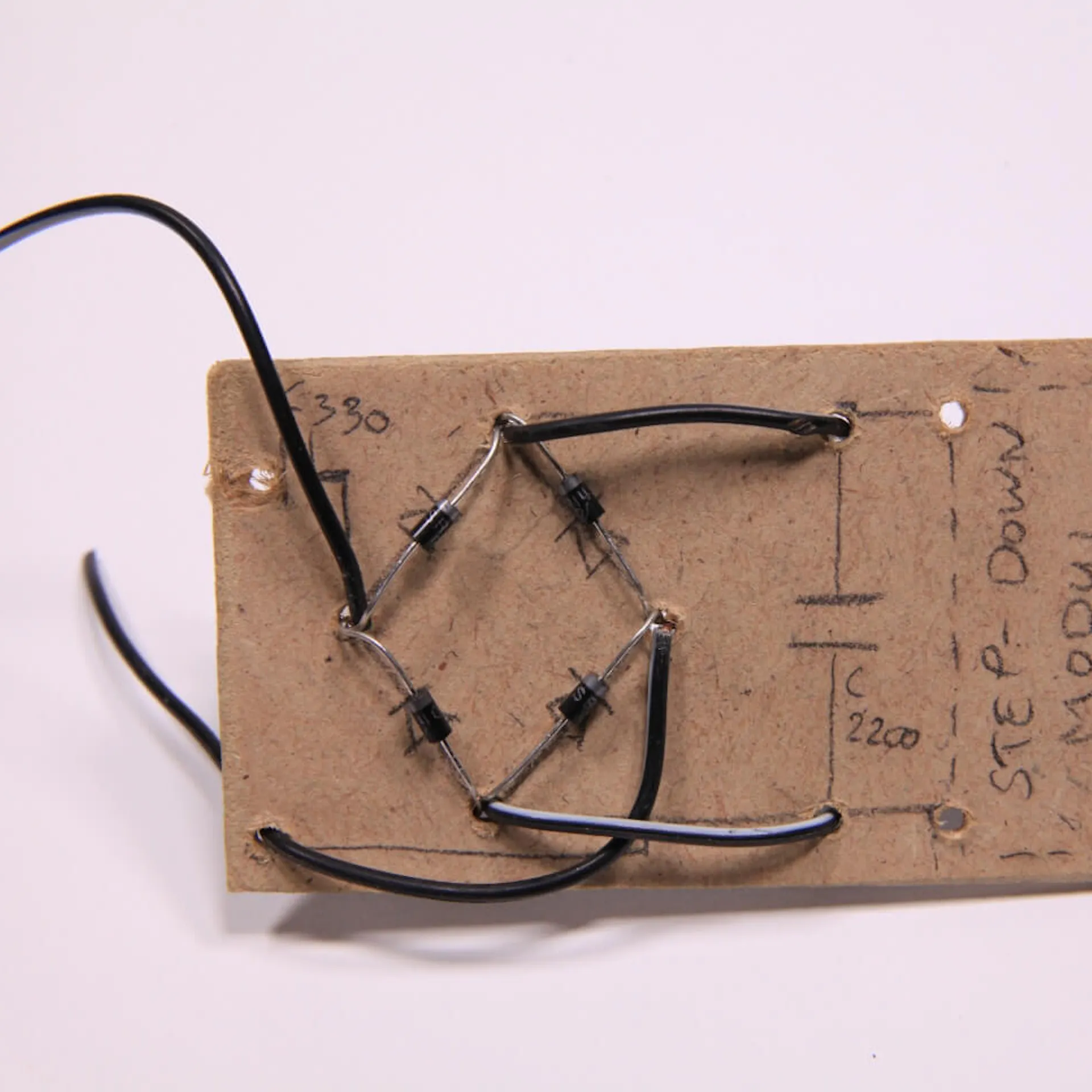 Kabel durch Bohrlöcher gesteckt durch eine Holzplatte mit Schaltplan und Dioden.