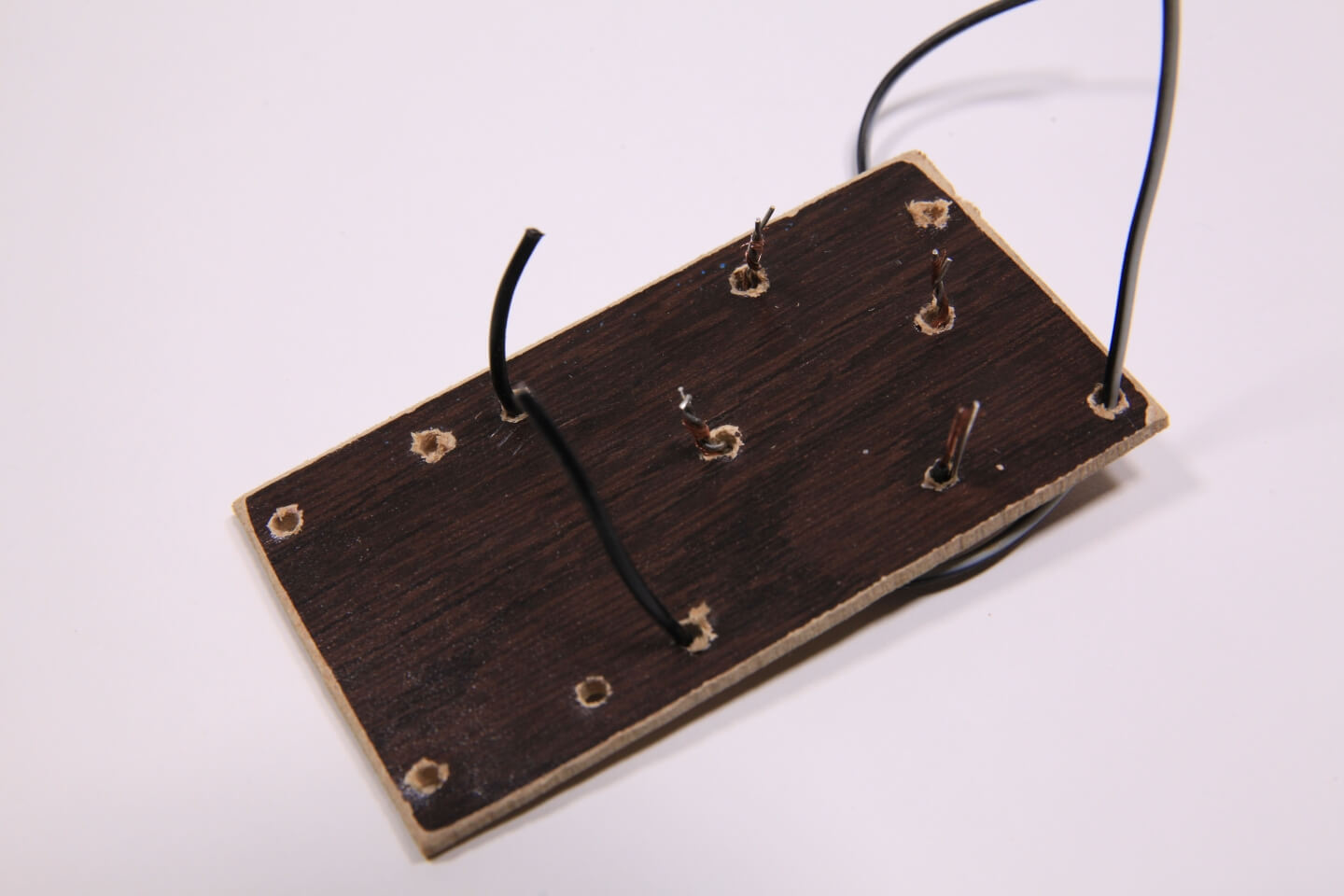 Kabel durch eine Holzplatte durchgesteckt.