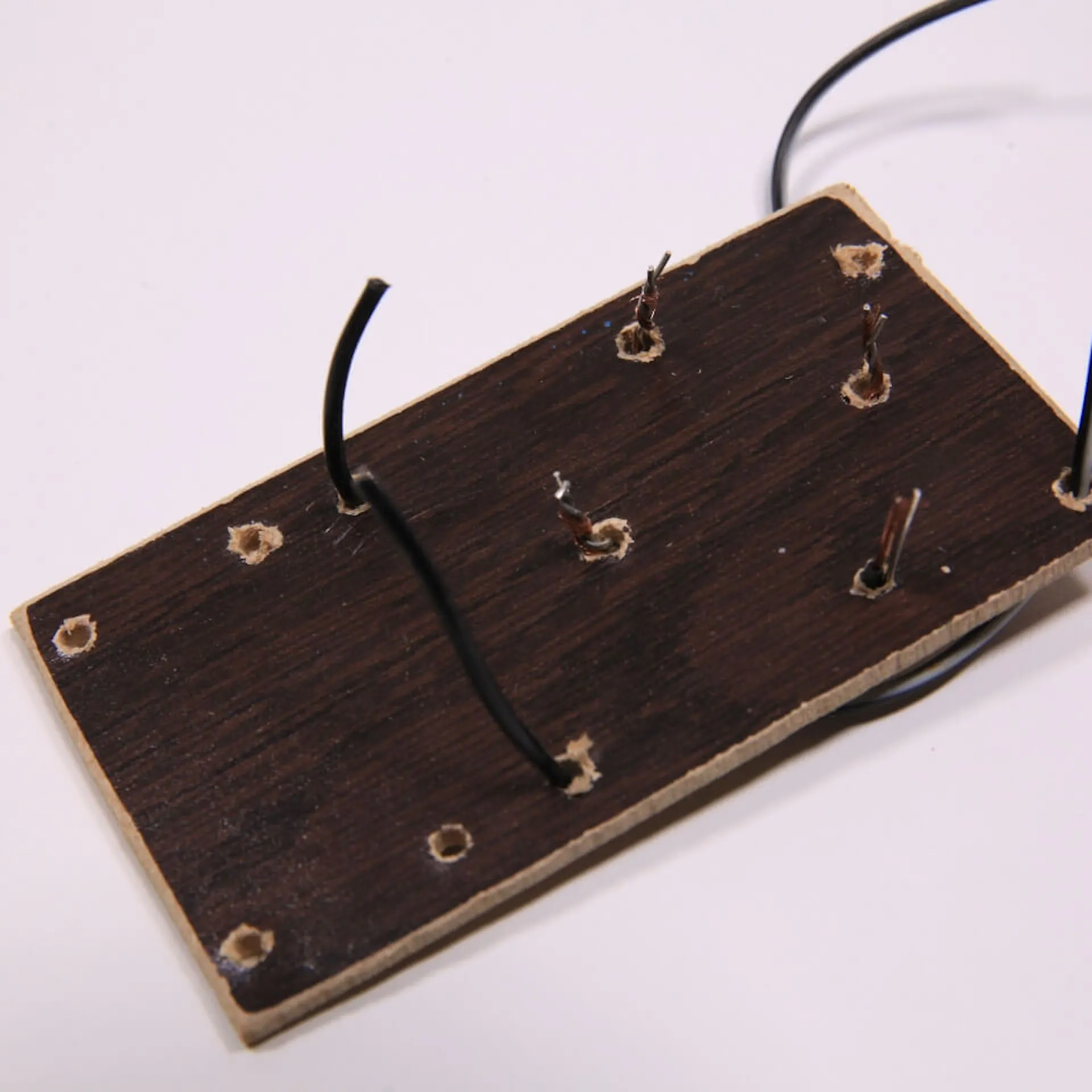 Kabel durch eine Holzplatte durchgesteckt.