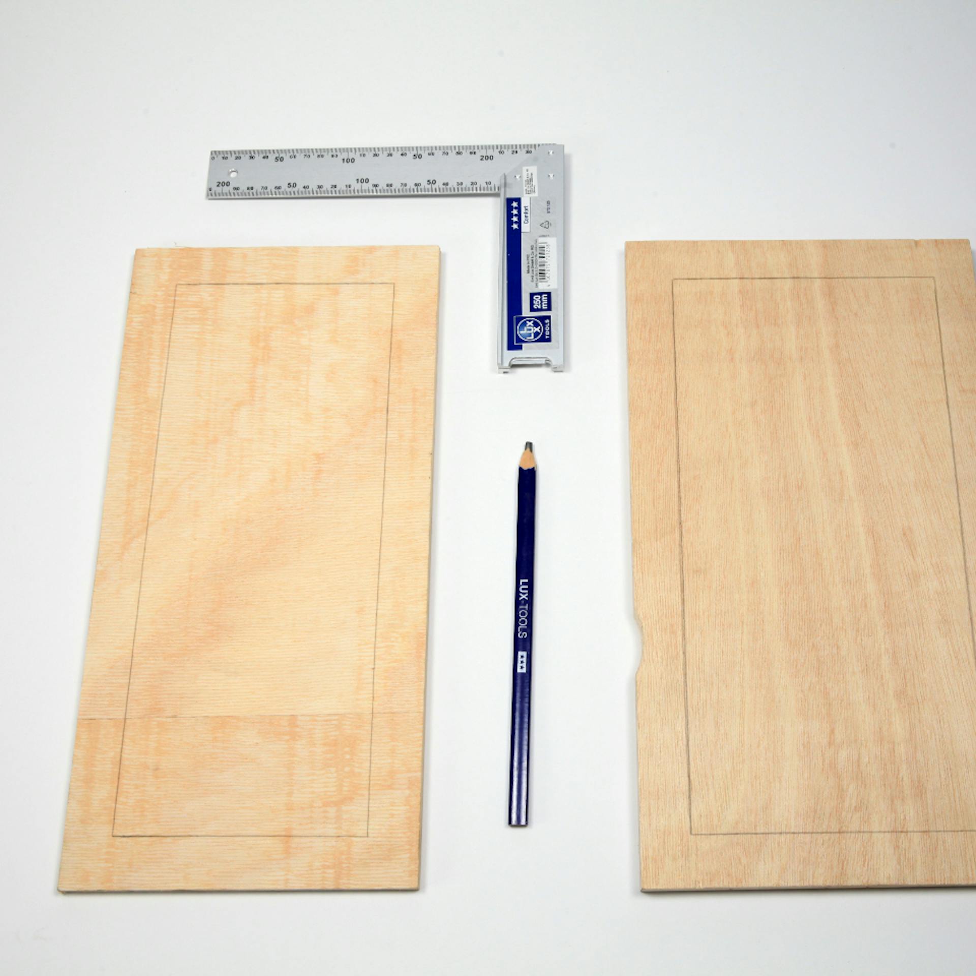 Zwei Holzbretter liegen neben Lineal und Bleistift mit aufgezeichneten Linien