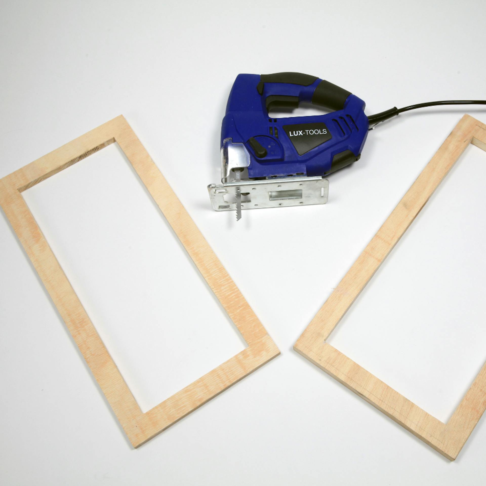 Stichsäge liegt neben ausgeschnittenen Rahmen aus Holzbrettern