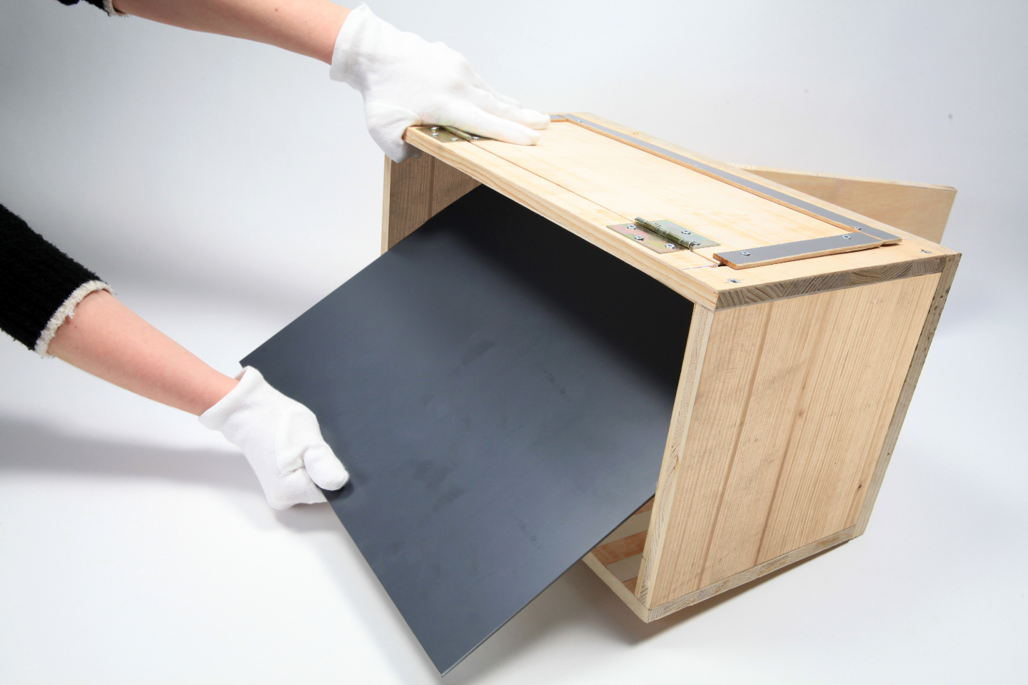 Person setzt Spiegel in offene Seite einer Holzbox ein.