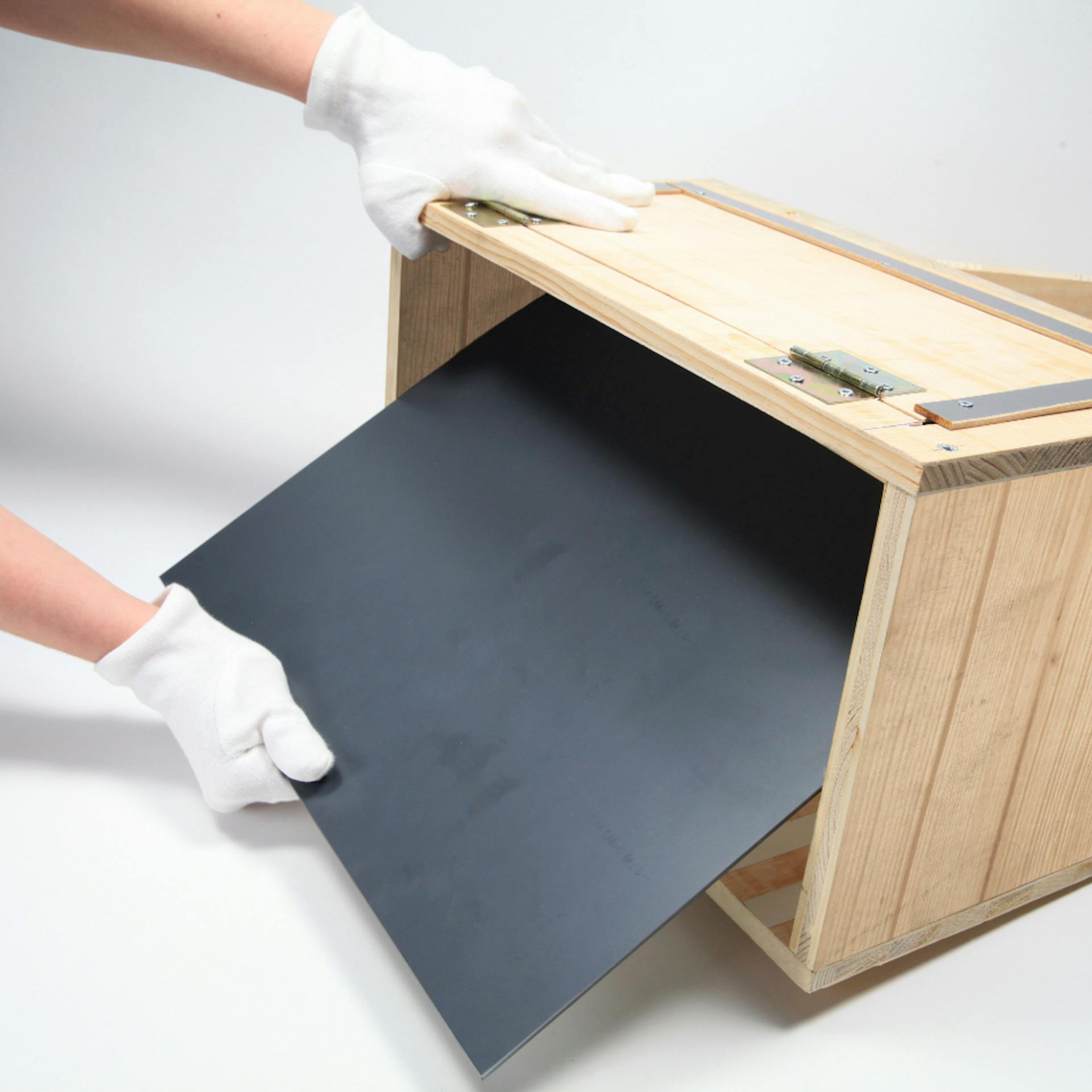 Person setzt Spiegel in offene Seite einer Holzbox ein.