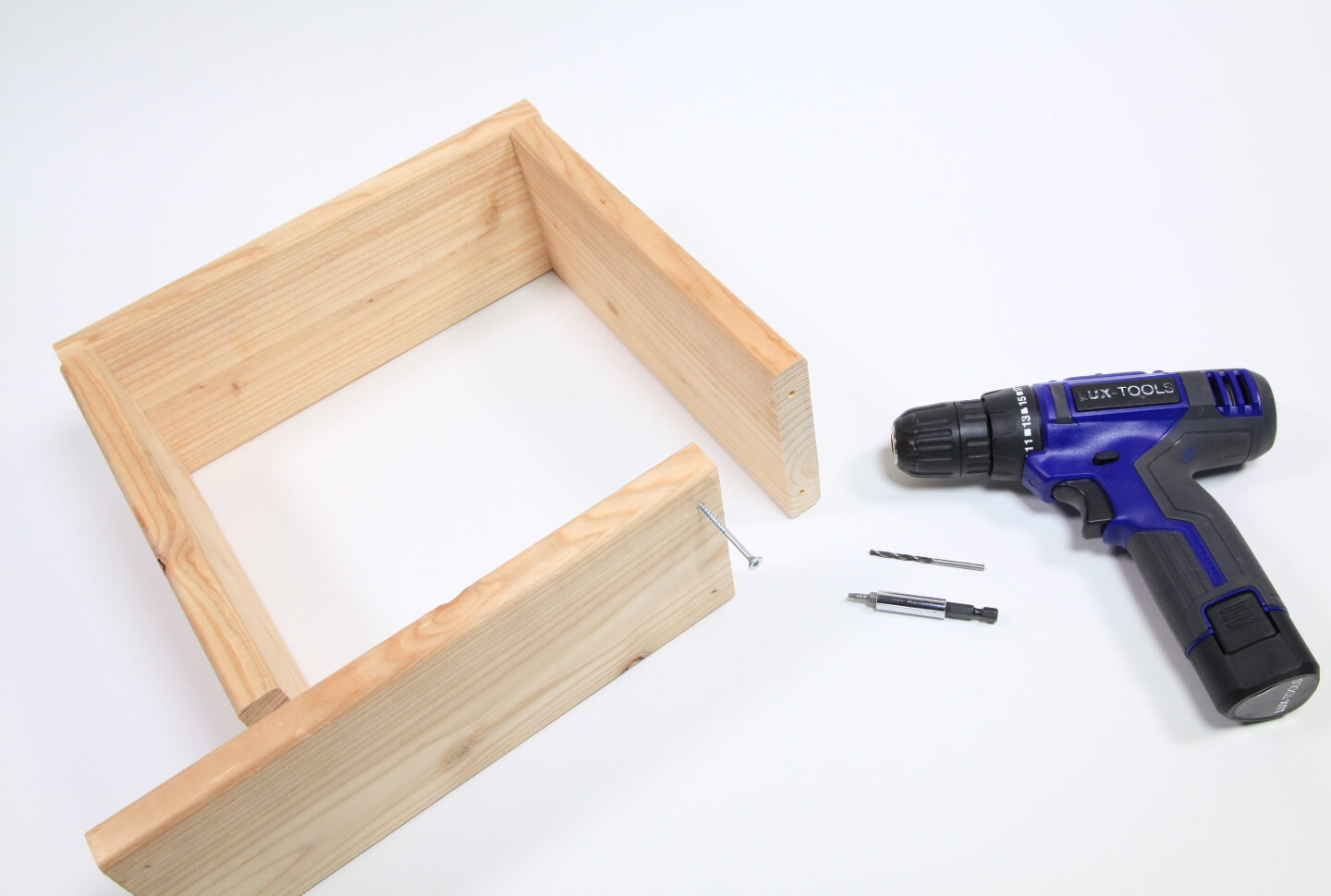 Egy fakeret látható, amelynek az egyik oldala még nincs összecsavarozva. Mellette egy akkus csavarozó különböző tartozékokkal