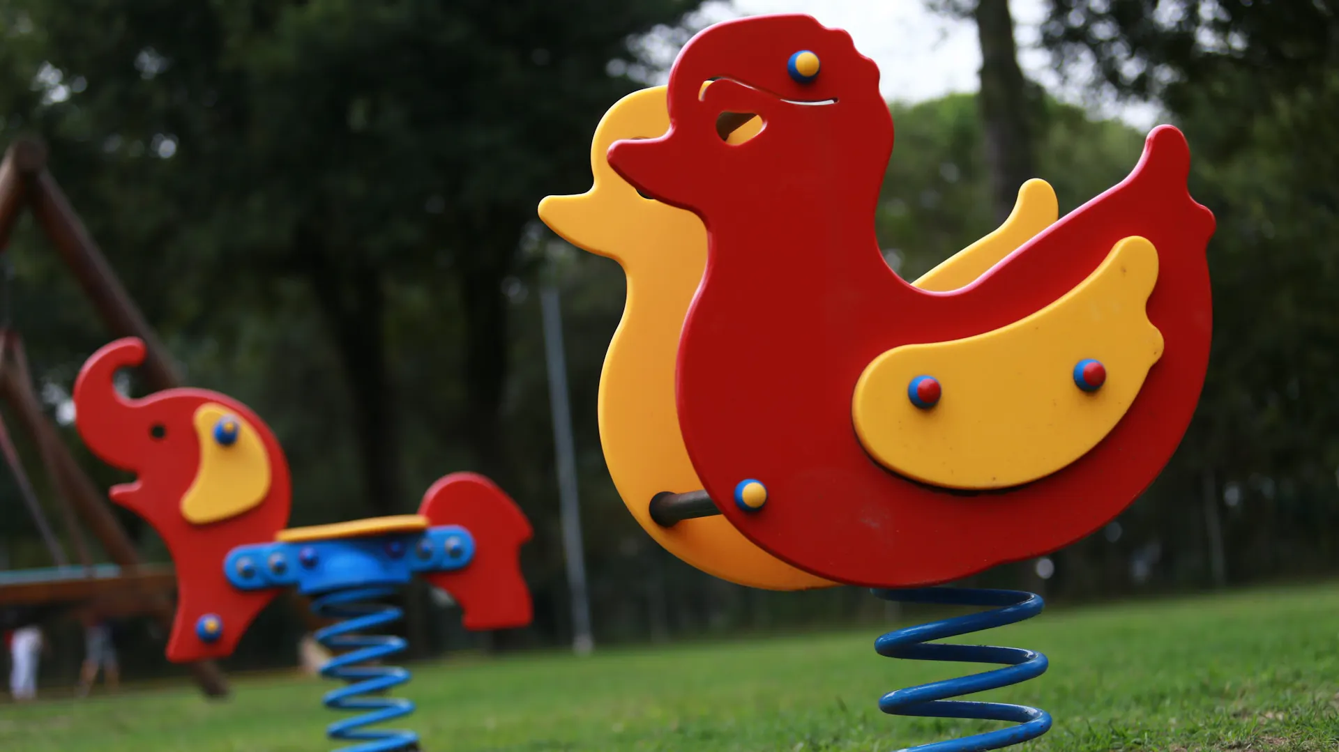Due altalene a molla a forma di anatra e di elefante in un parco giochi