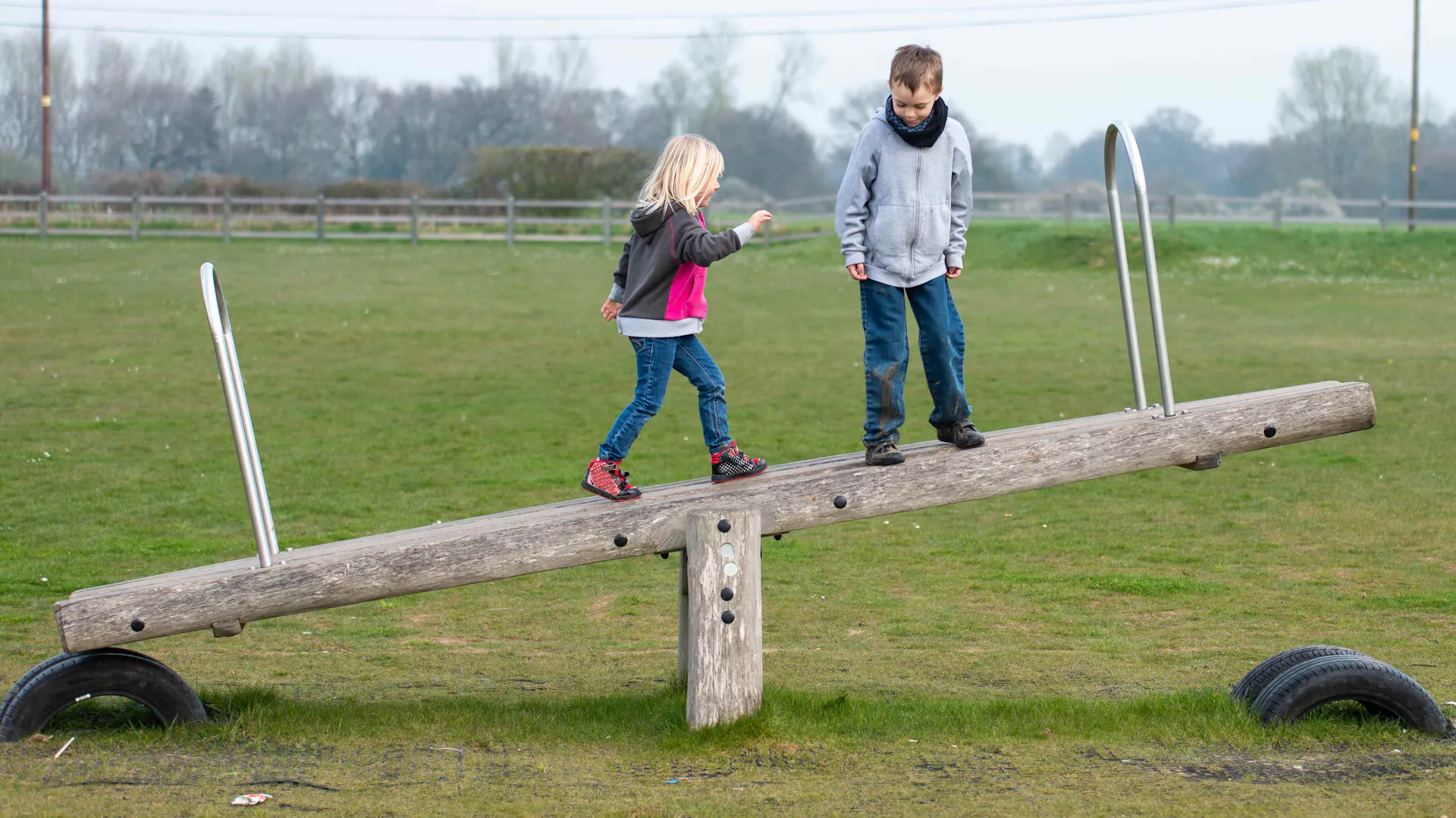 Due bambini camminano su un’asse basculante di legno