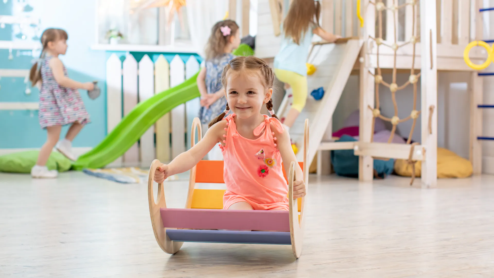 Una bambina gioca su un dondolo arcobaleno