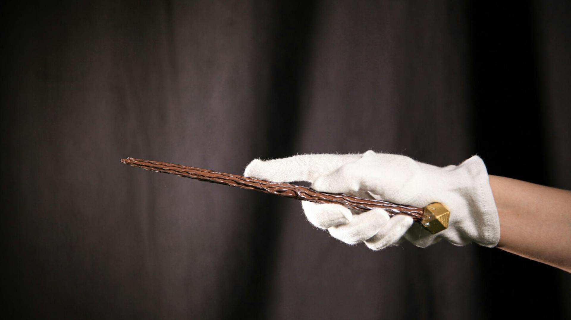 Eine Person, die einen weißen Handschuh trägt, hält einen selbstgemachten Zauberstab in der Hand.