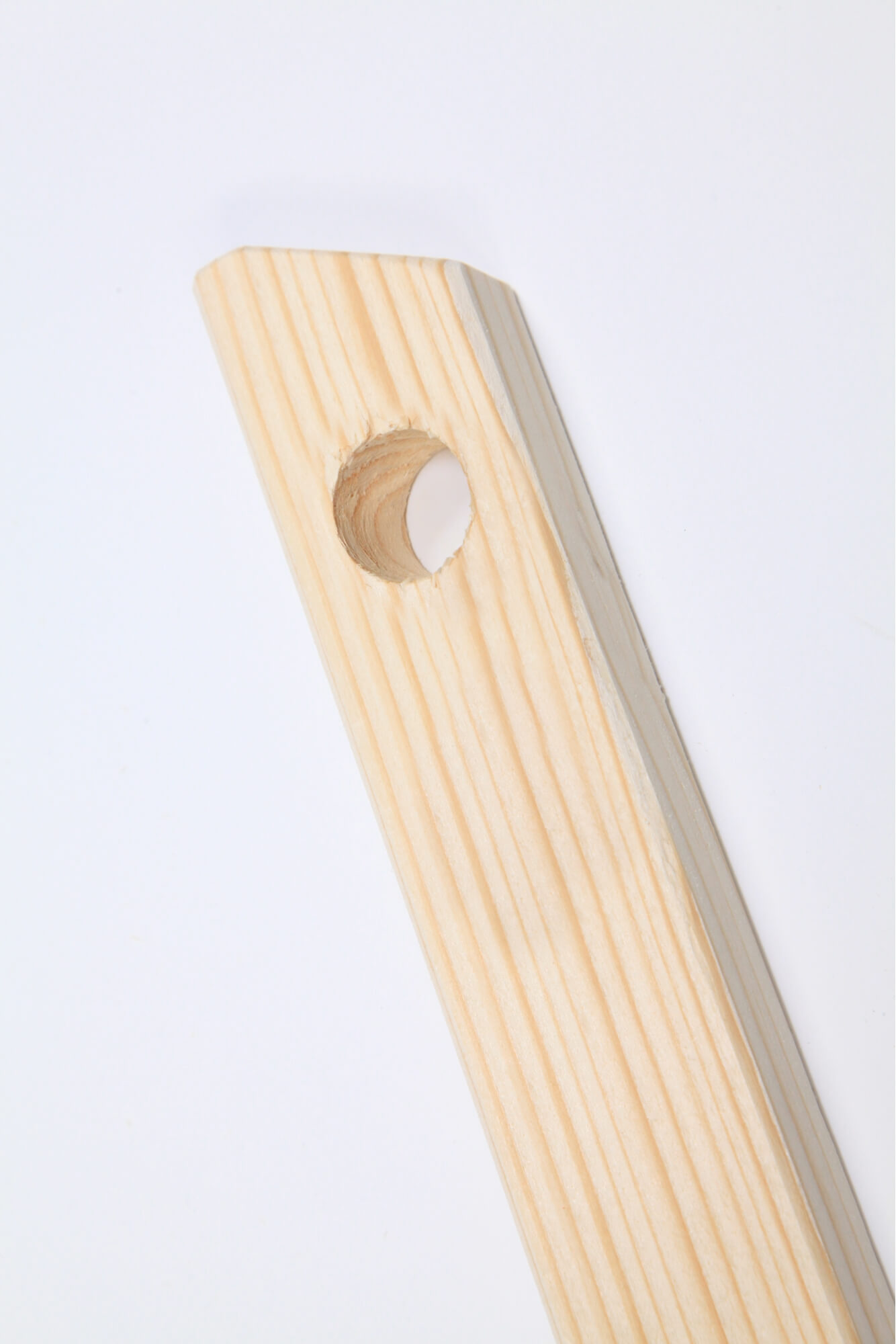 Estremità di una trave in legno su sfondo bianco. Al centro della trave è presente un foro circolare.