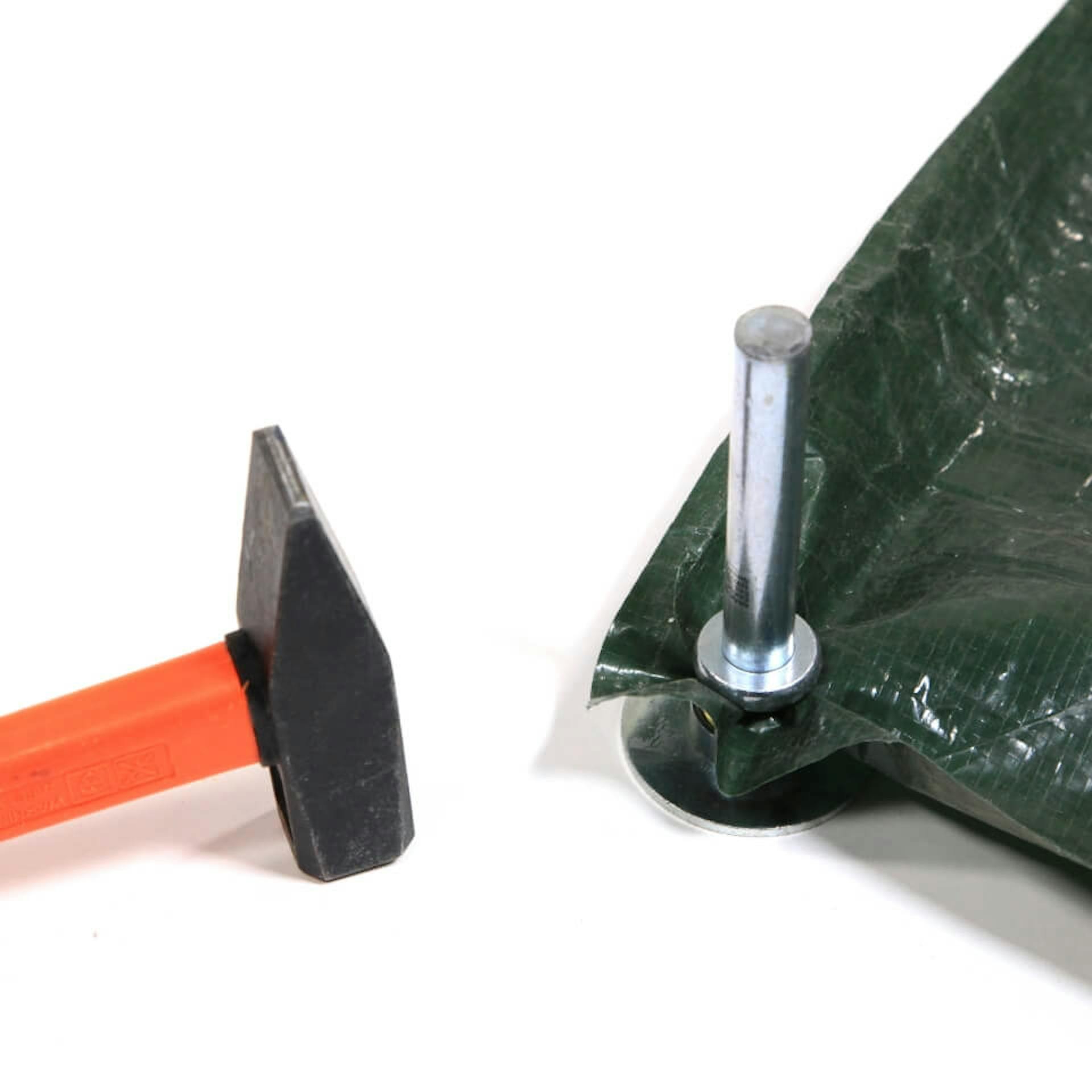 Es ist die Ecke einer dunklen Plane zu sehen. An dieser wird mit Werkzeug eine Öse befestigt. Daneben liegt ein Hammer.