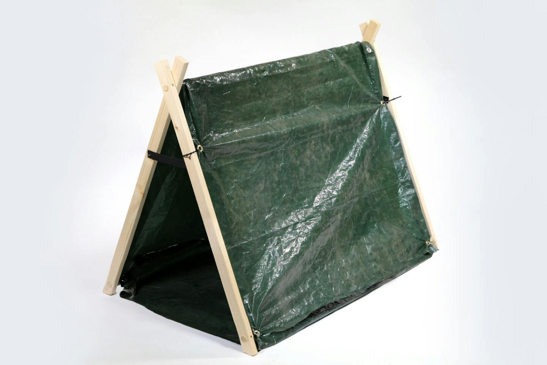 Una piccola tenda su sfondo bianco. Il telaio è costituito da elementi di legno, il tetto è un telo scuro.