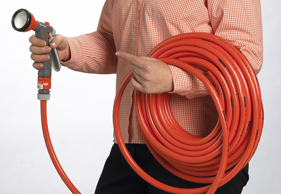 Jemand hält einen aufgerollten Gartenschlauch mit Brause.