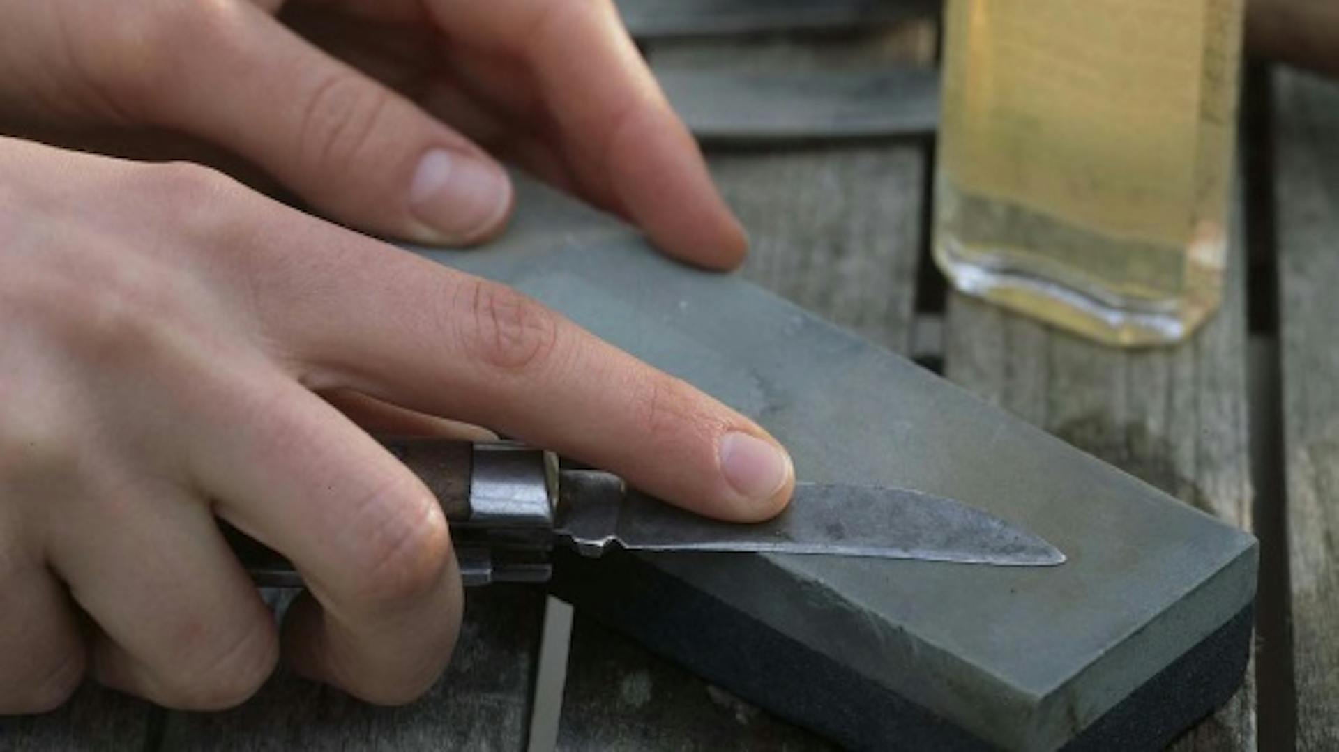 Jemand schärft ein Messer mit einem Schleifstein.