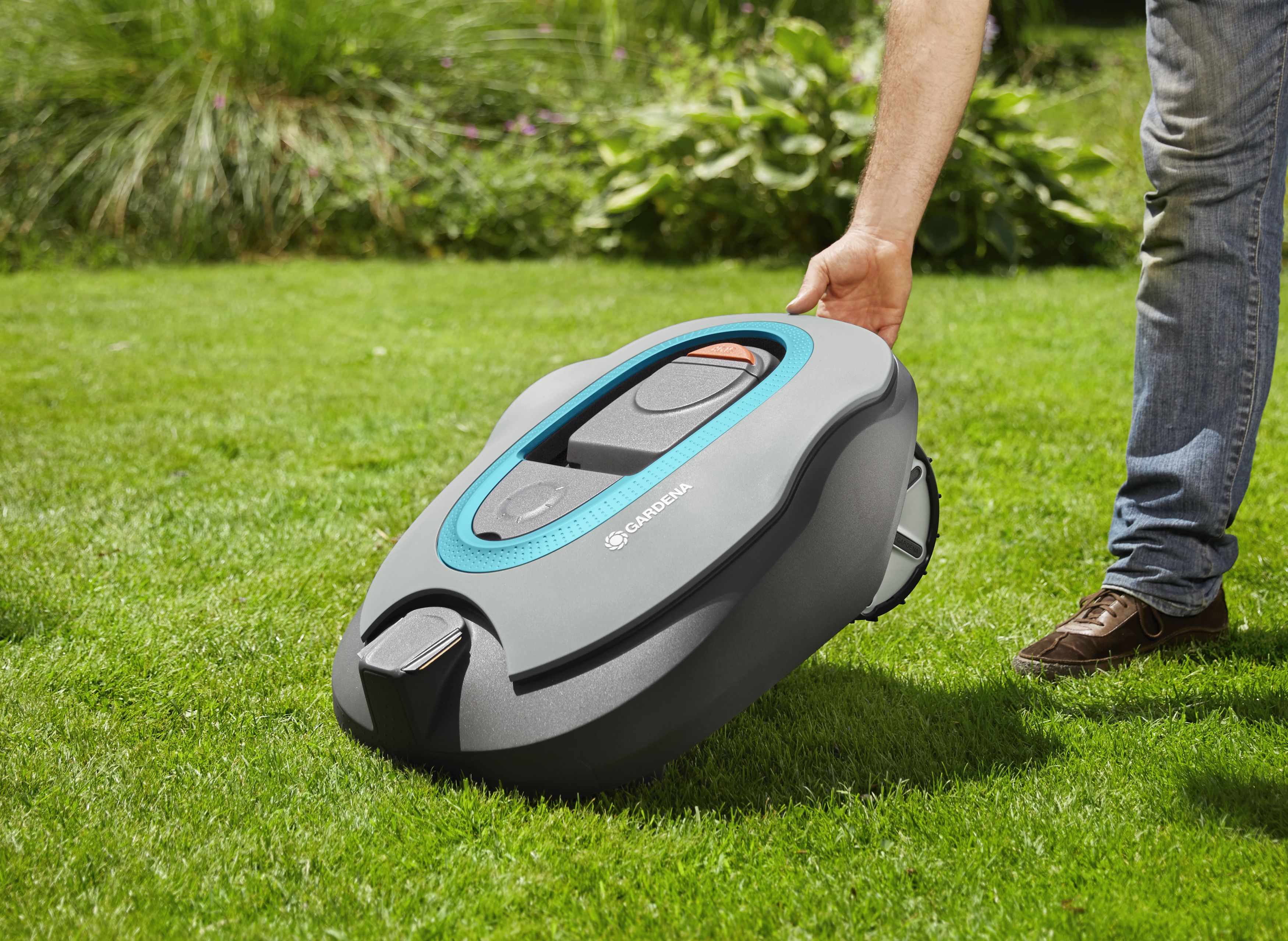 Hand hebt Mähroboter hoch