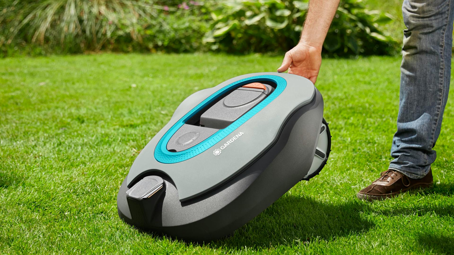 Hand hebt Mähroboter hoch