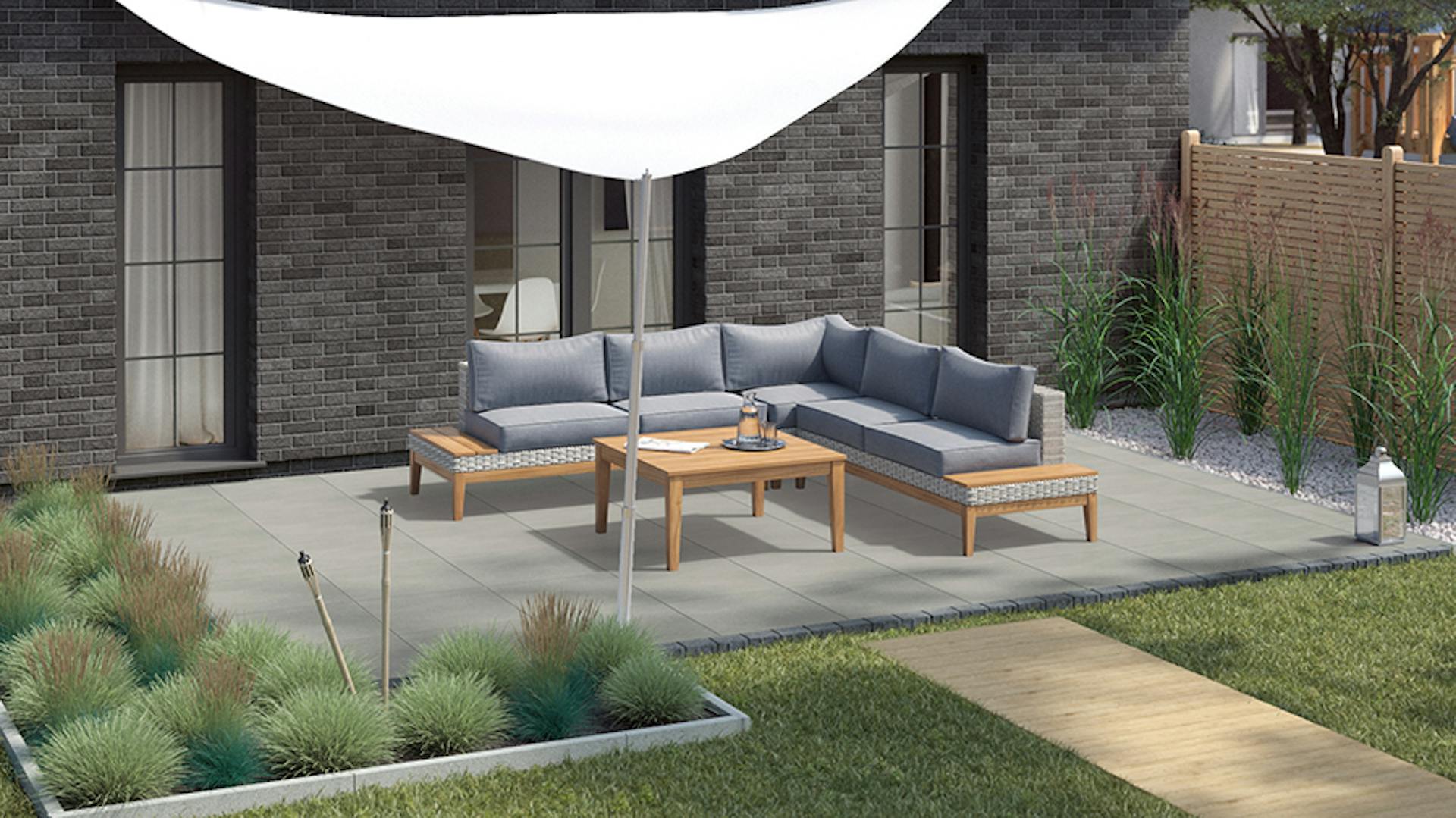 Gartengestaltung moderne Terrasse mit Loungegruppe auf Steinboden unter Sonnensegel an eckigen eingefassten Beeten mit Gräsern neben hohem Holzzaun als Sichtschutz