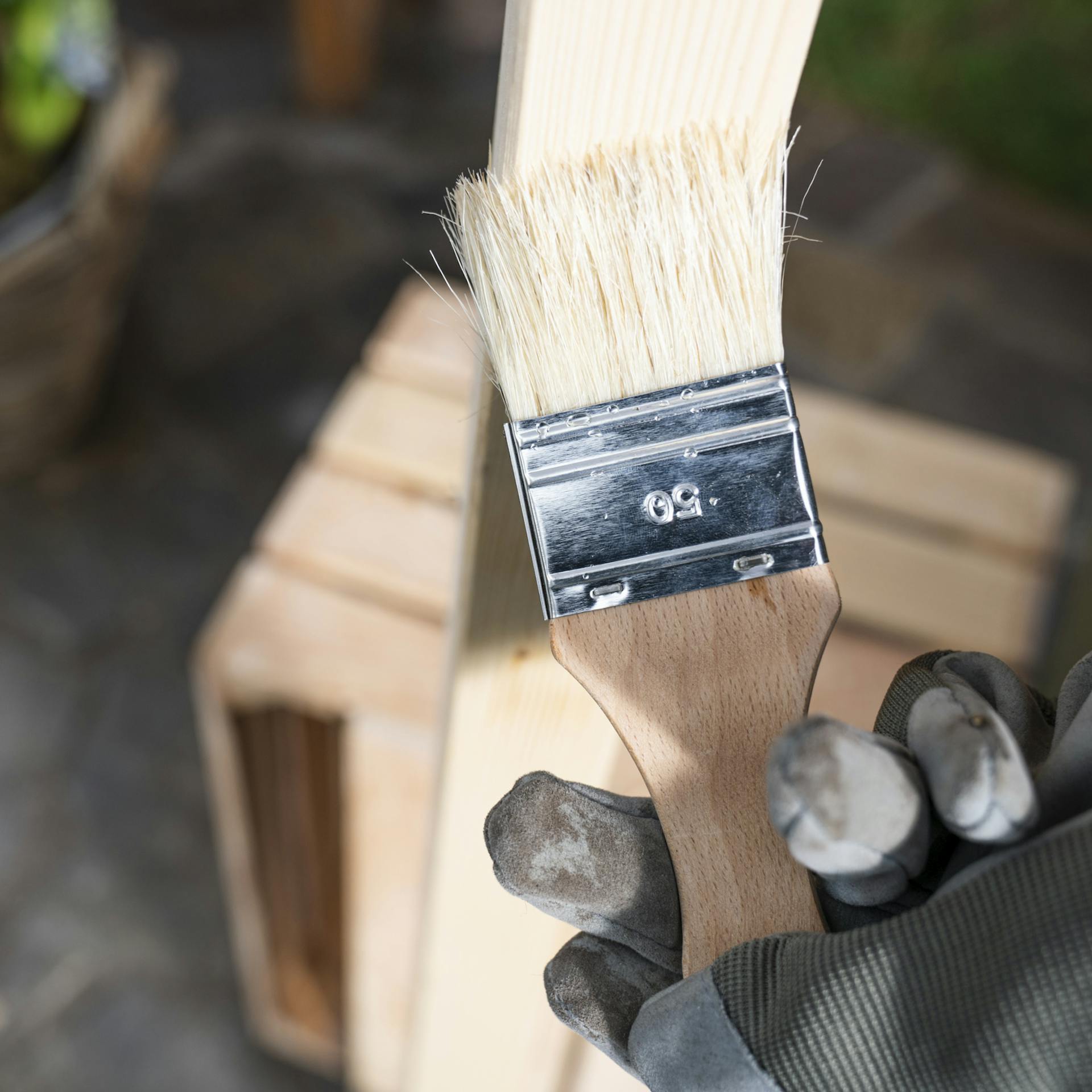 Das senkrechtstehende Vierkantholz wird mit Holz-Öl eingestrichen.