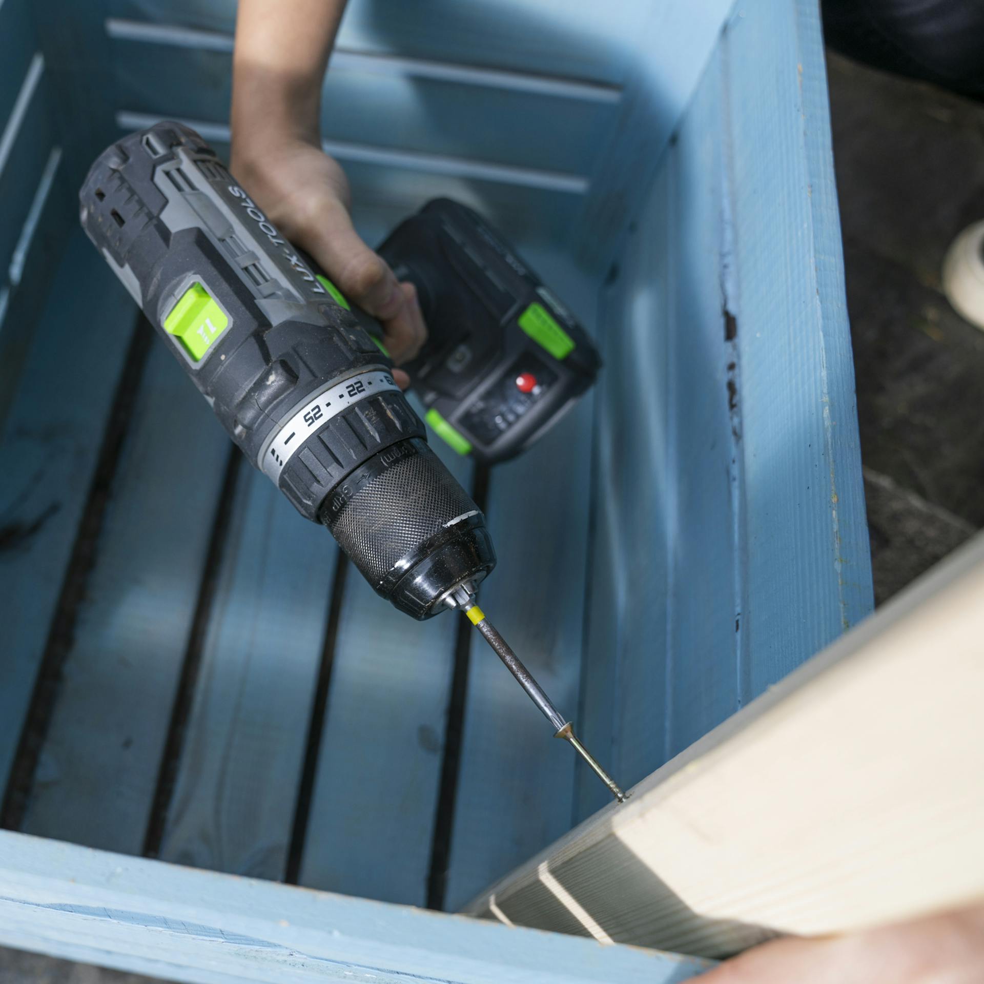 Das Vierkantholz wird in der Ecke der Pflanzkiste mit einem Akkuschrauber verschraubt.