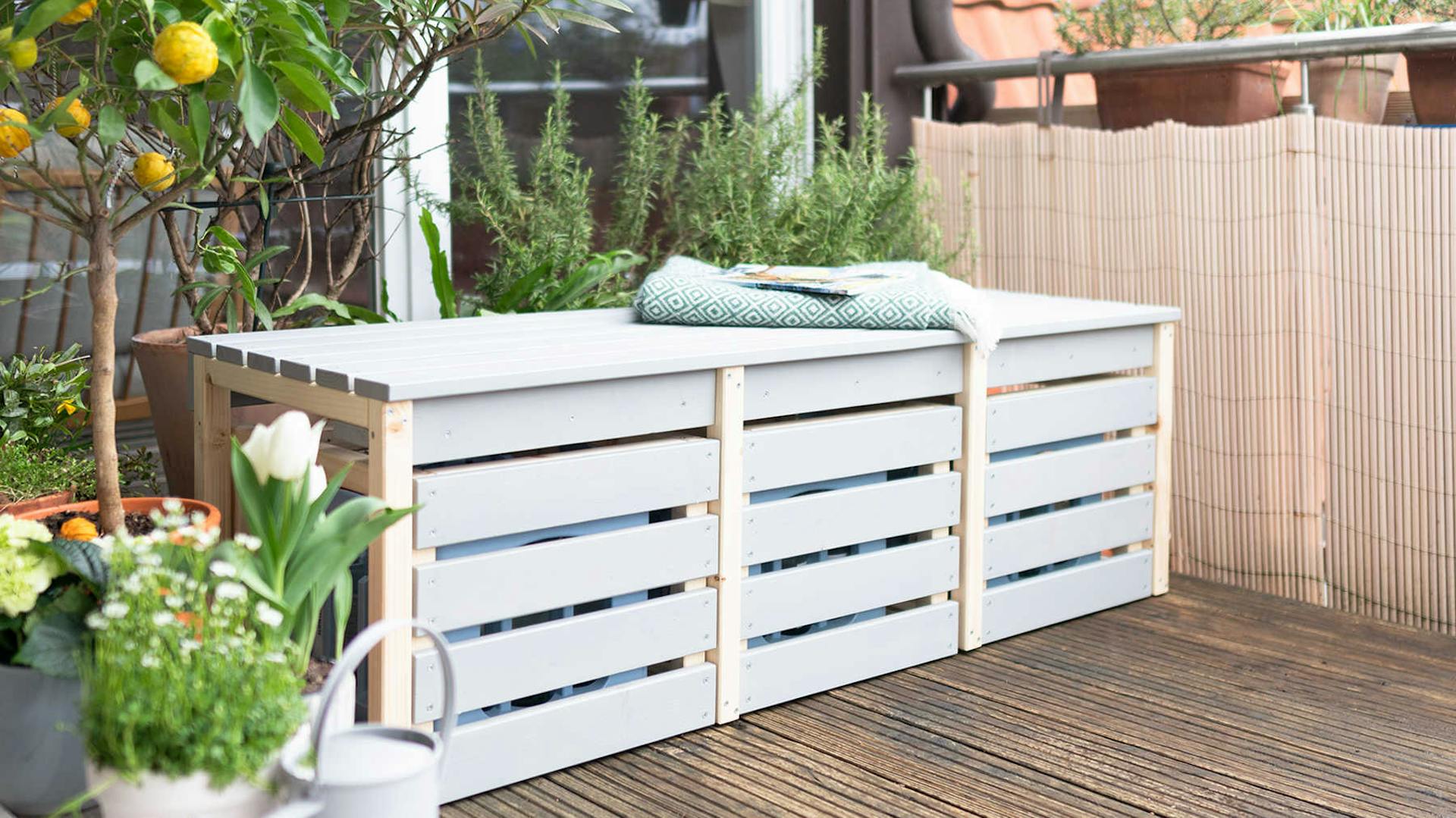 Seitliche Ansicht des aus Vollholz bestehenden Balkonbank Lasse in graublau mit viel Stauraum.