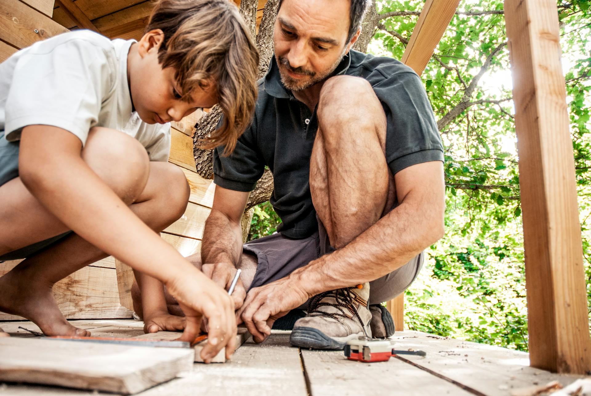 Padre e figlio posano assi per il pavimento della casa sull'albero.