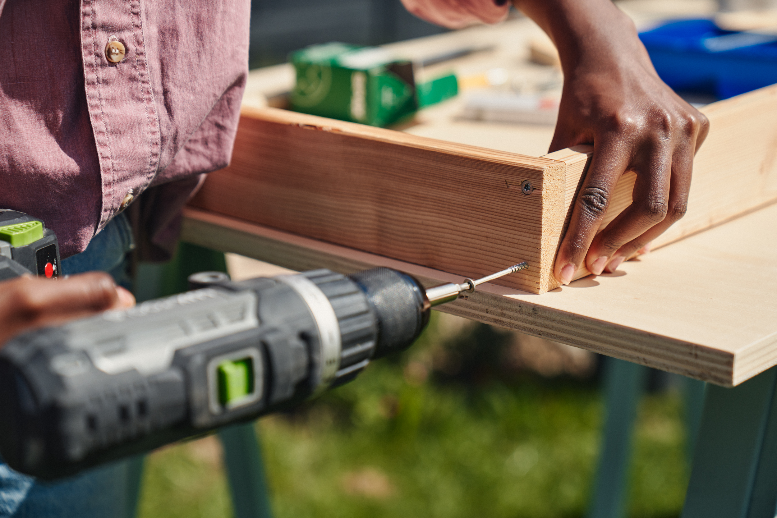 Egy nő deszkákat csavaroz össze egy akkus csavarhúzóval.