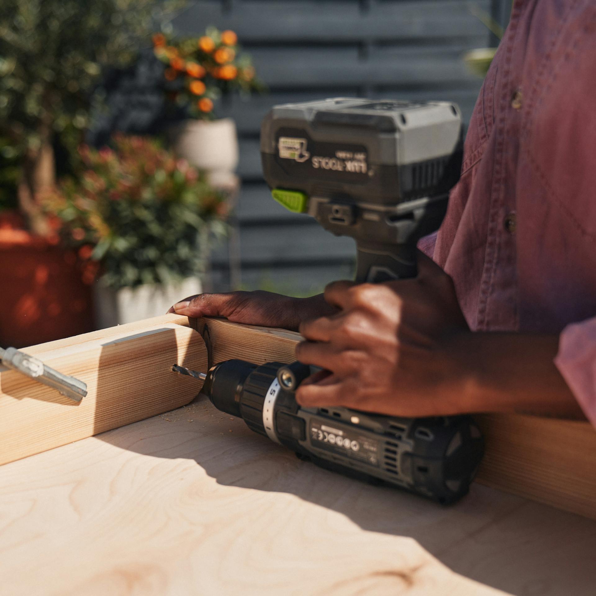 Egy nő lyukat fúr egy fadarabba.