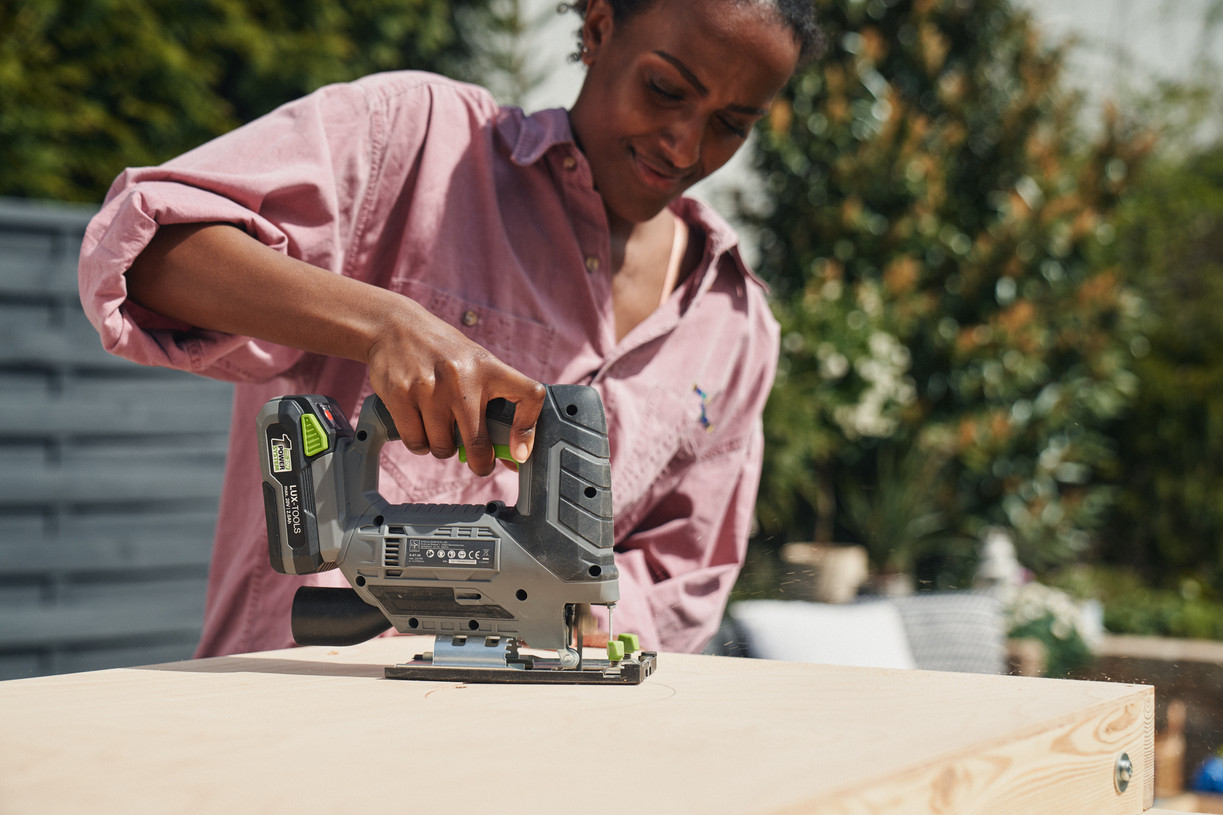 A nő fűrésszel lyukat fűrészel a fakeretbe.