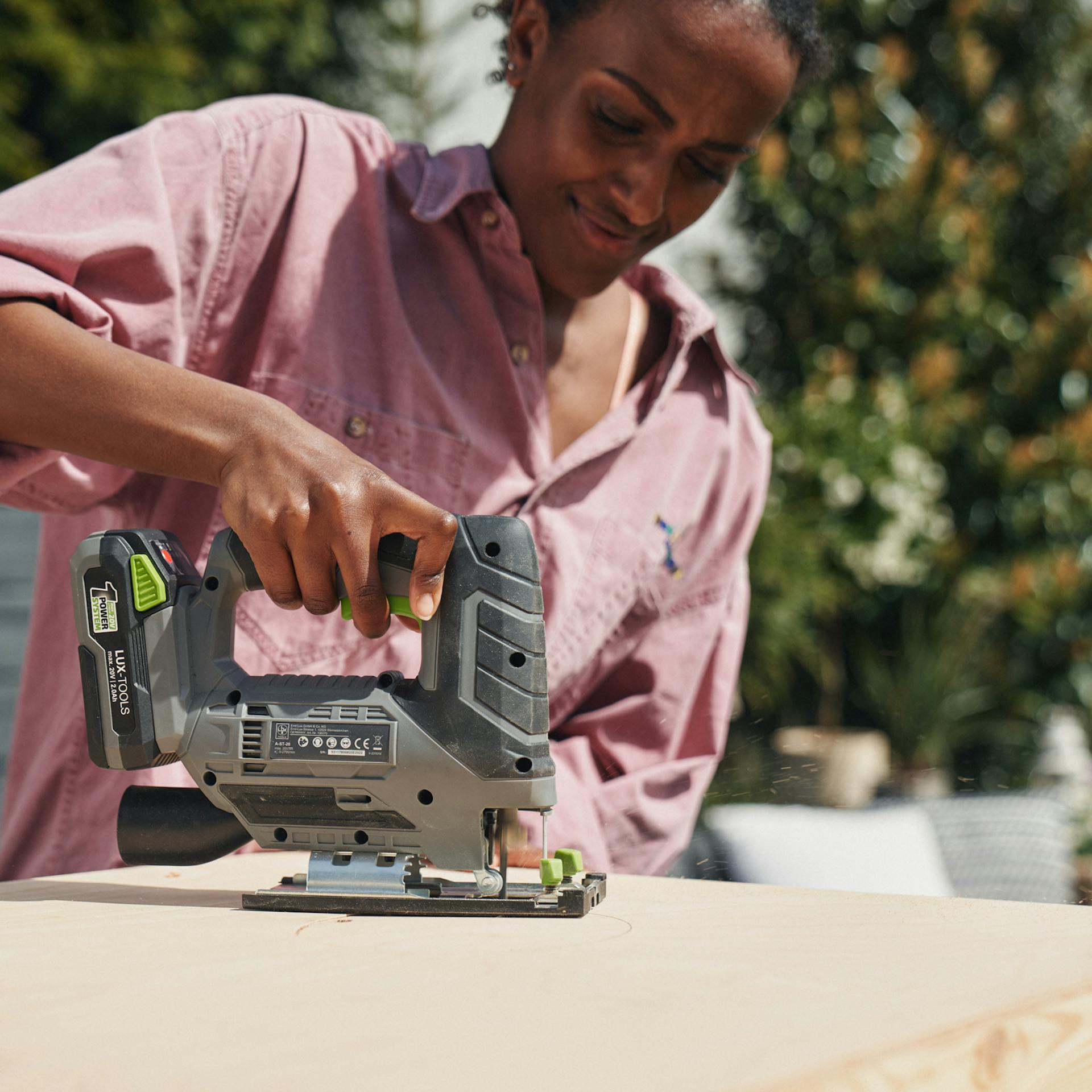 A nő fűrésszel lyukat fűrészel a fakeretbe.