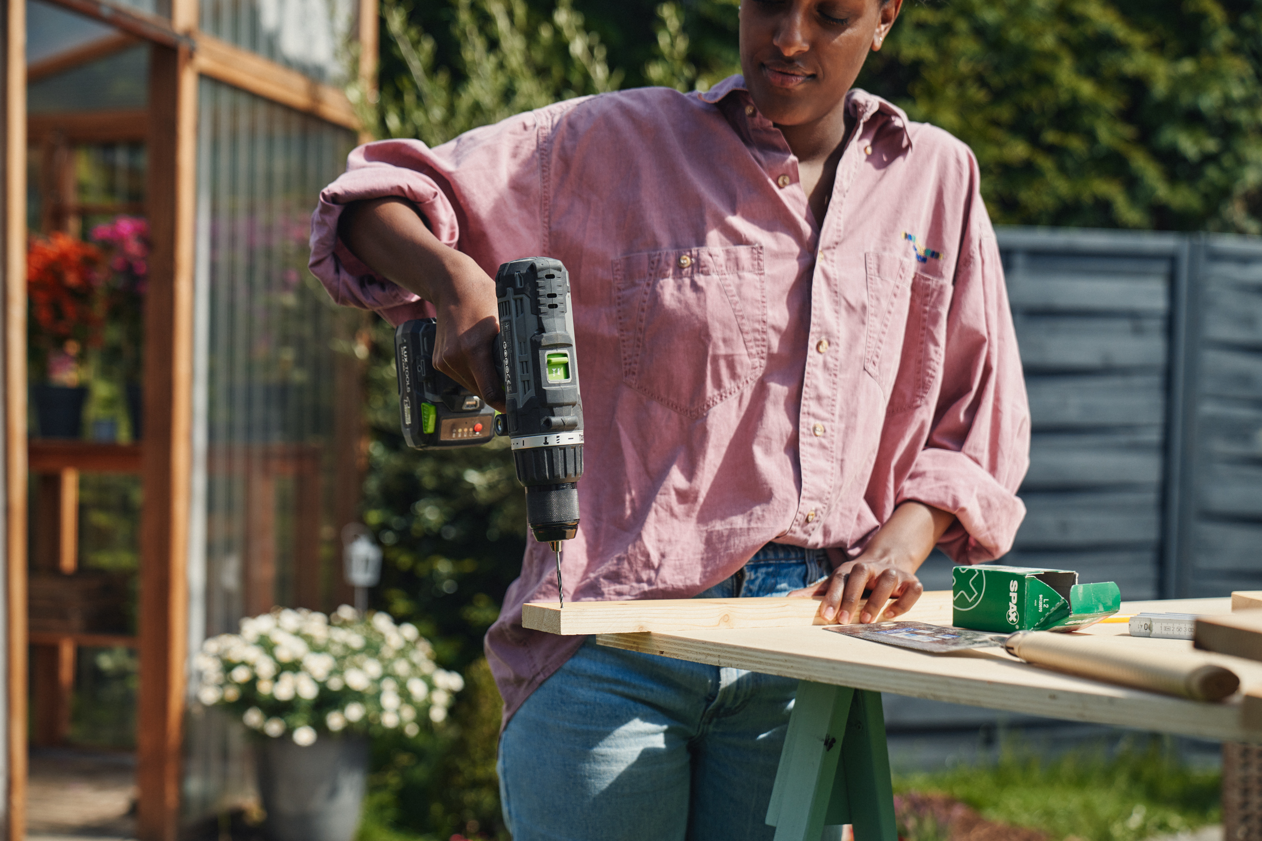 Egy nő lyukakat fúr egy fadarabba.