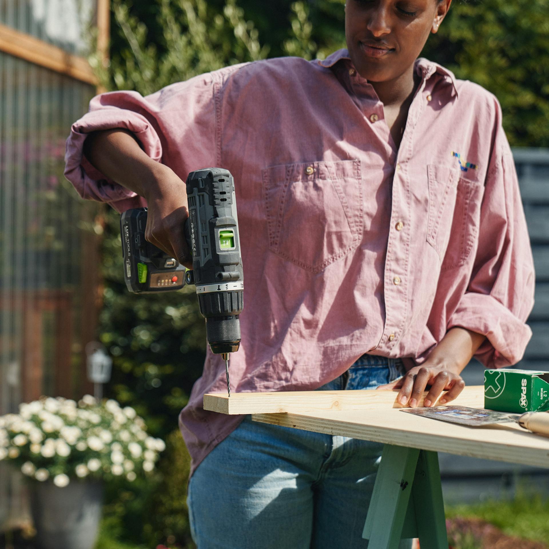 Egy nő lyukakat fúr egy fadarabba.