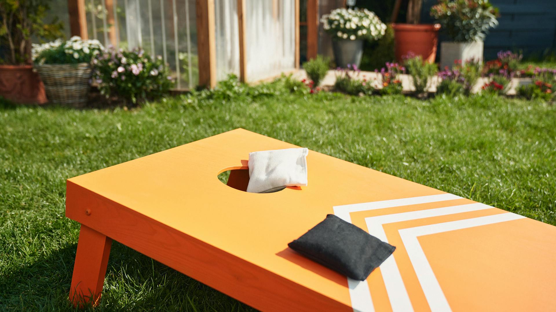 Naracssárgára festett babzsákdobó tábla áll a fűben két zsákkal