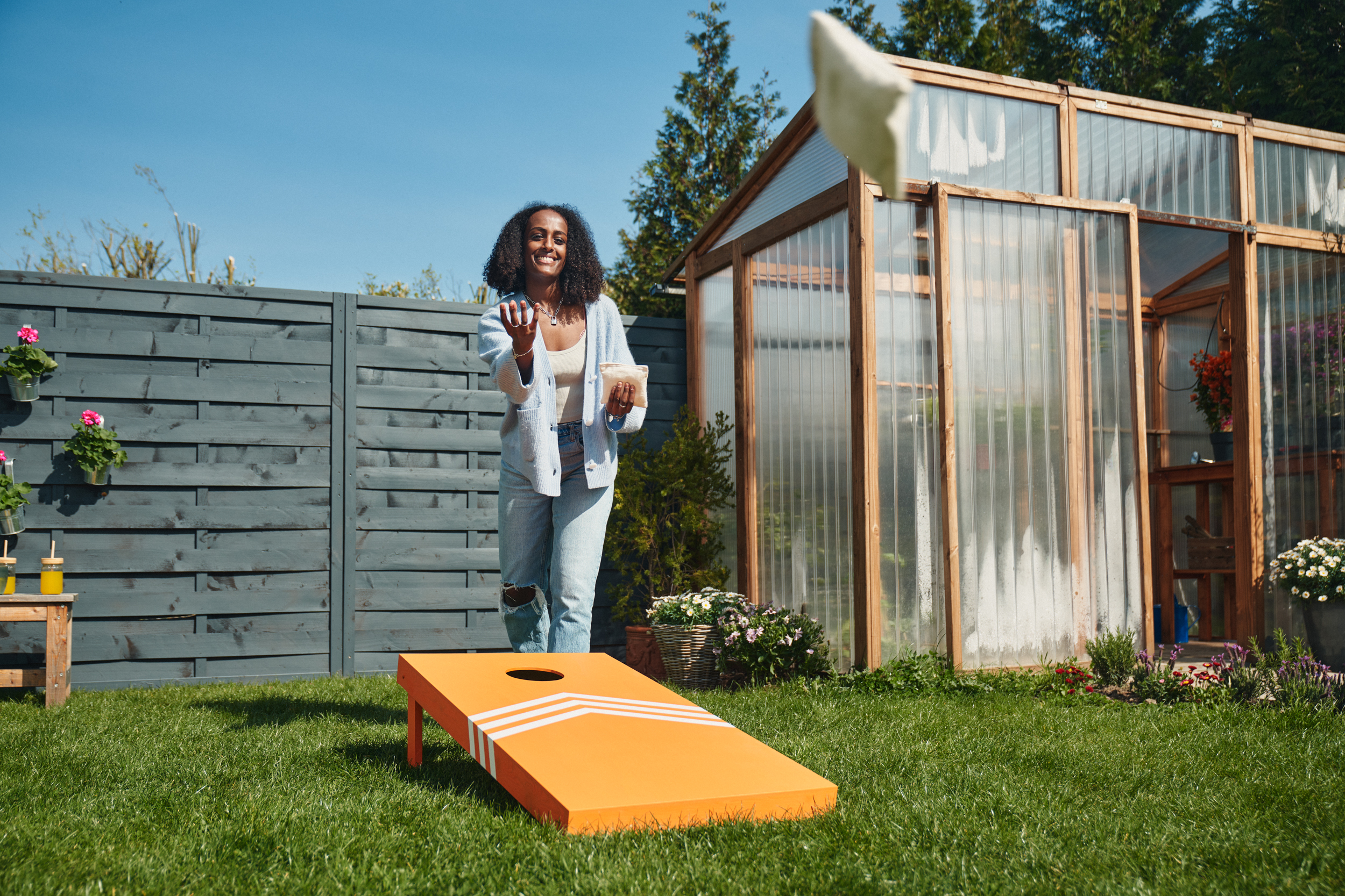 Egy lány a kezében zsákkal, előtte pedig egy naracsságára festett babzsákdobó céltábla