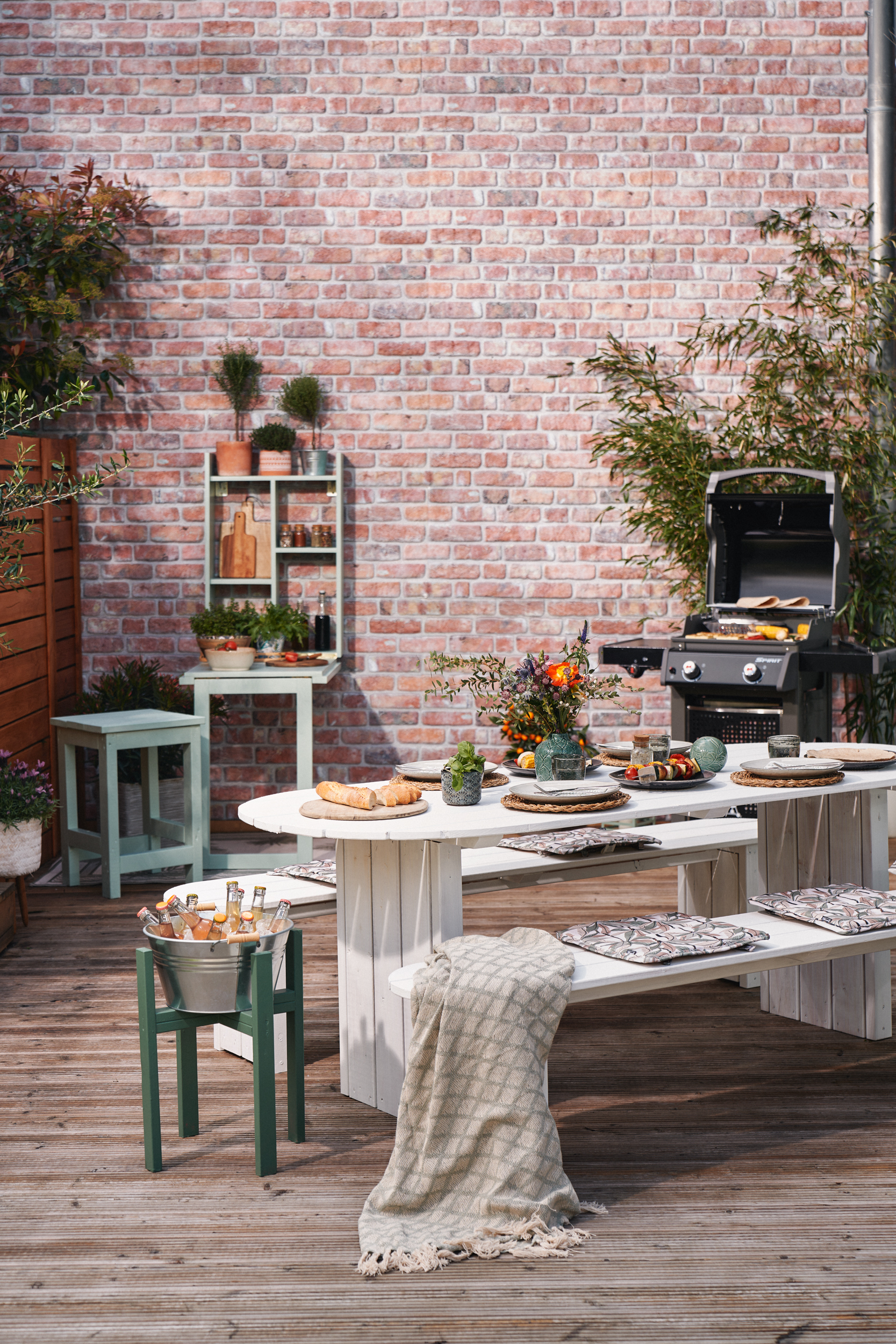 Rozložený grilovací stůl s prostřeným stolem v popředí
